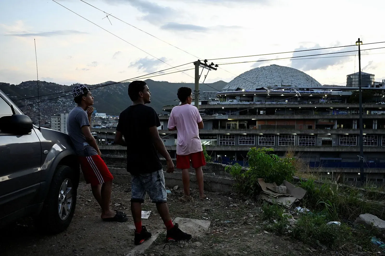 مجموعة من الشباب في كراكاس، فنزويلا، يتأملون منحدرًا حضريًا، مع خلفية تظهر معالم المدينة، في سياق مناقشة قانون العفو عن السجناء السياسيين.