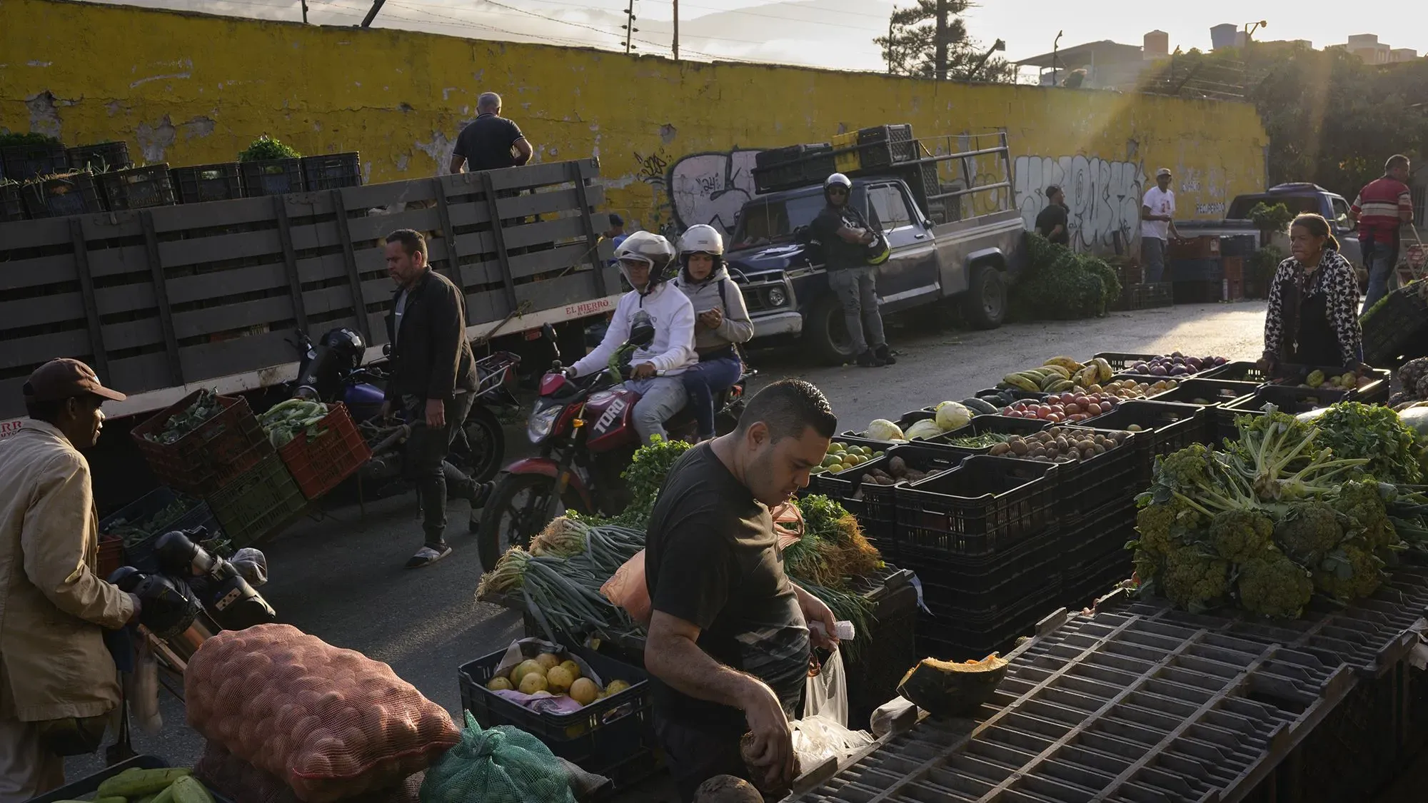 سوق شعبي في فنزويلا يعرض خضروات وفواكه، مع وجود بائعين وزبائن، في ظل ظروف اقتصادية صعبة ونقص في السلع الأساسية.