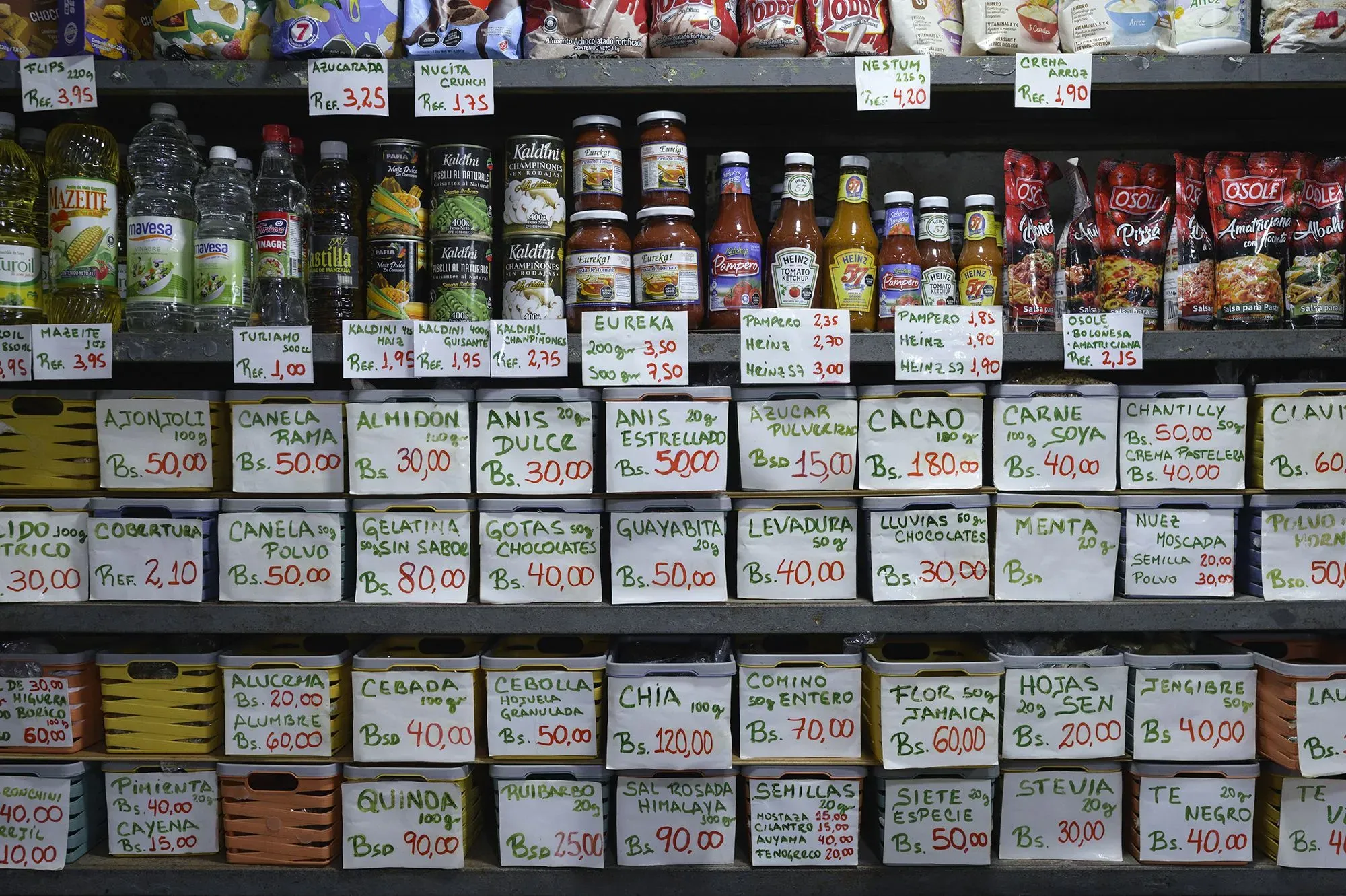 رفوف متجر تعرض مجموعة متنوعة من المواد الغذائية، مع تسعيرات مكتوبة على بطاقات، تعكس التضخم وندرة السلع الأساسية في فنزويلا.