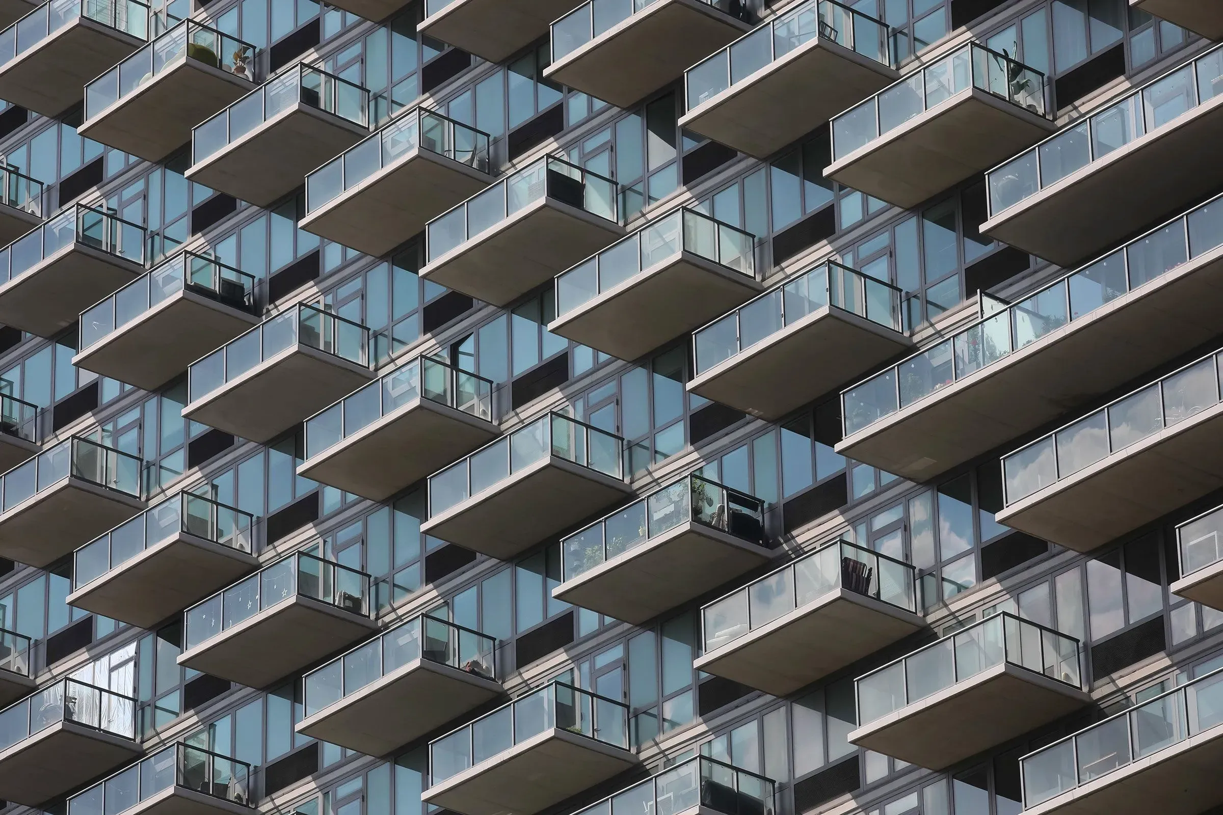 واجهة مبنى سكني حديث في مدينة نيويورك، تظهر شرفات زجاجية متعددة، تعكس الحاجة الملحة لمشاريع الإسكان بأسعار معقولة.