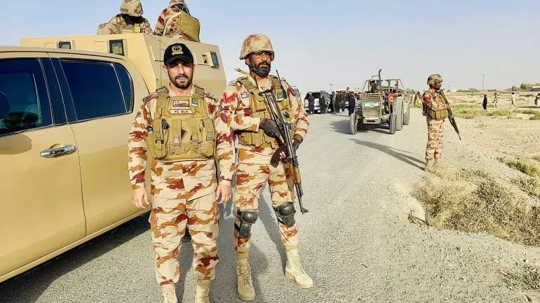 جنود من الجيش الباكستاني يقفون على جانب الطريق في منطقة حدودية، مع مركبات عسكرية في الخلفية، وسط توتر متزايد بين أفغانستان وباكستان.
