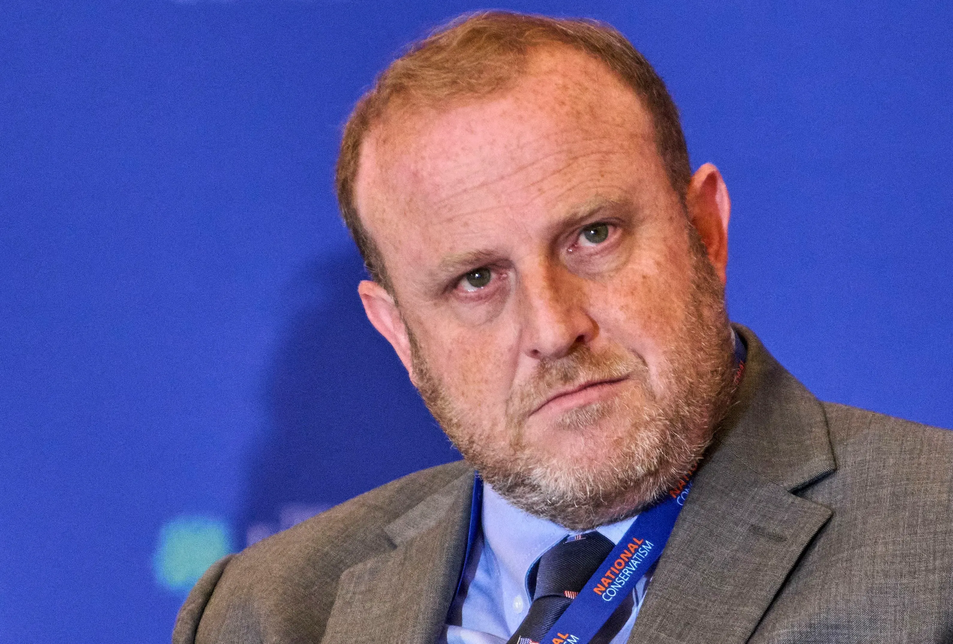 صورة لجيريمي كارل، مرشح وزارة الخارجية، يظهر فيها بملابس رسمية وخلفية زرقاء، تعكس جدلاً حول تصريحاته السابقة على وسائل التواصل الاجتماعي.