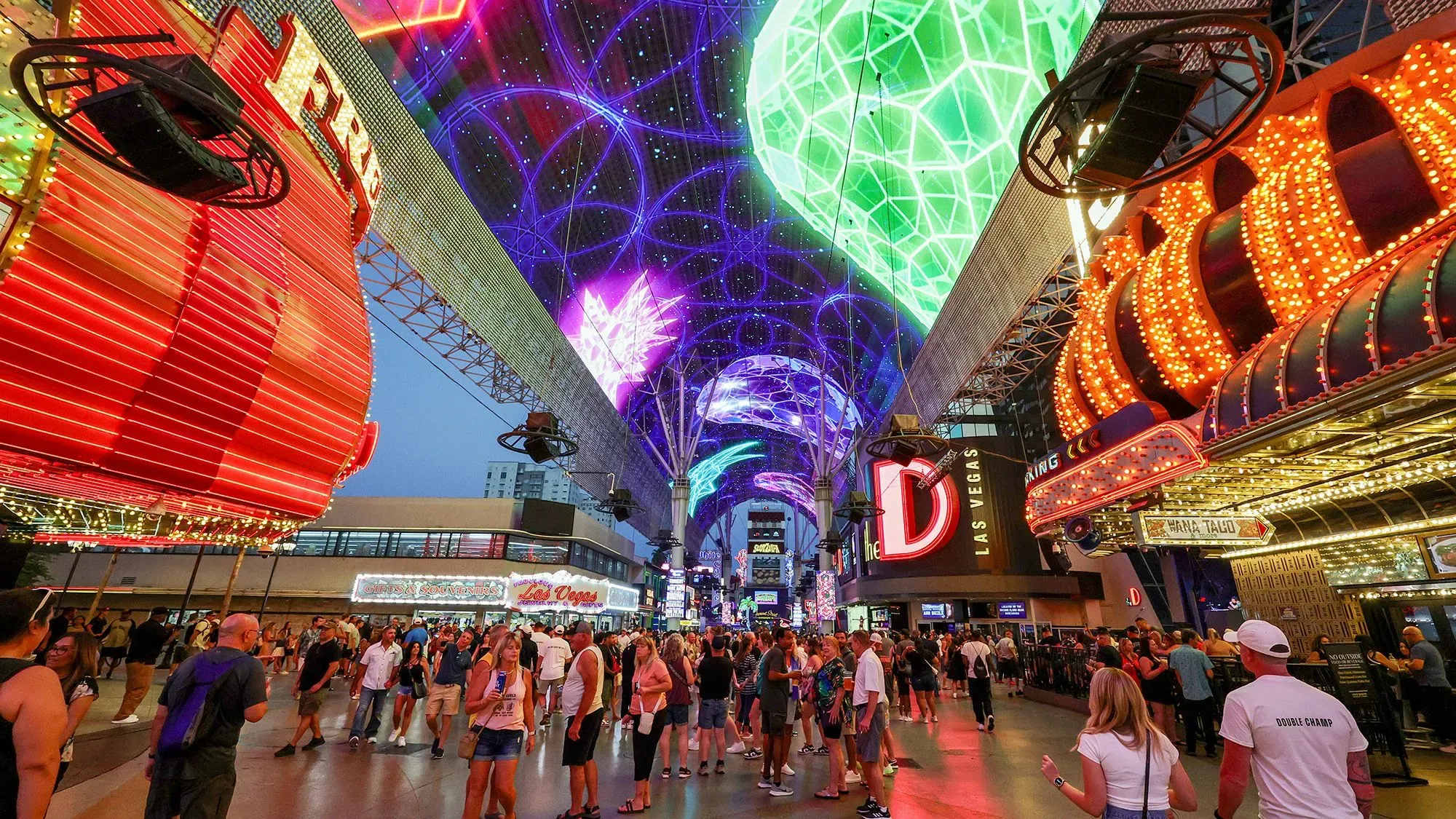 شارع فريمونت في لاس فيغاس، مزدحم بالزوار تحت الأضواء الساطعة، مع لافتات كازينوهات ملونة تعكس تراجع السياحة الكندية.