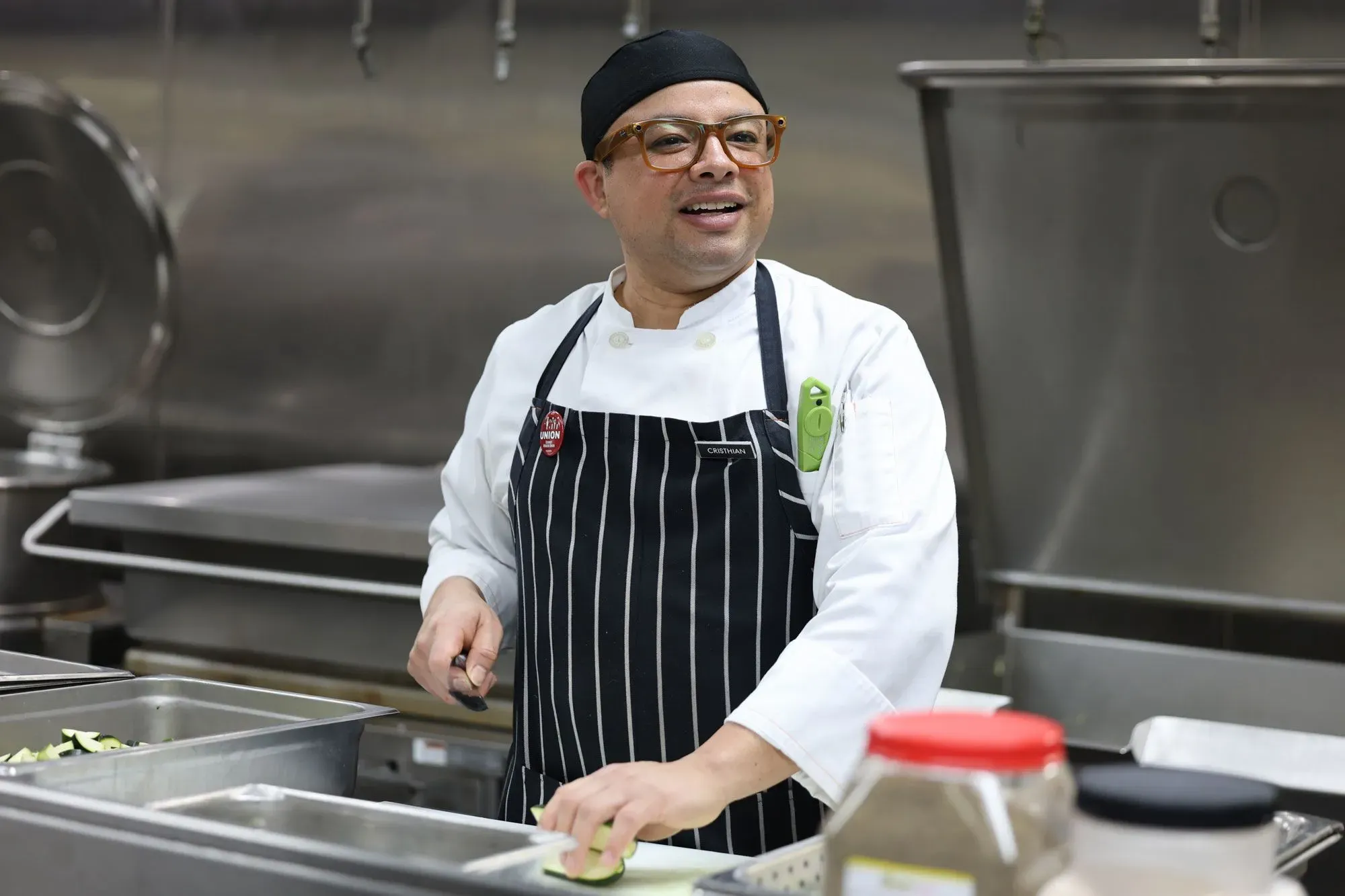 طاهٍ يعمل في مطبخ كازينو في لاس فيغاس، يقطع الخضار بينما تحيط به معدات الطهي، في إطار جهود لجذب السياح الكنديين.