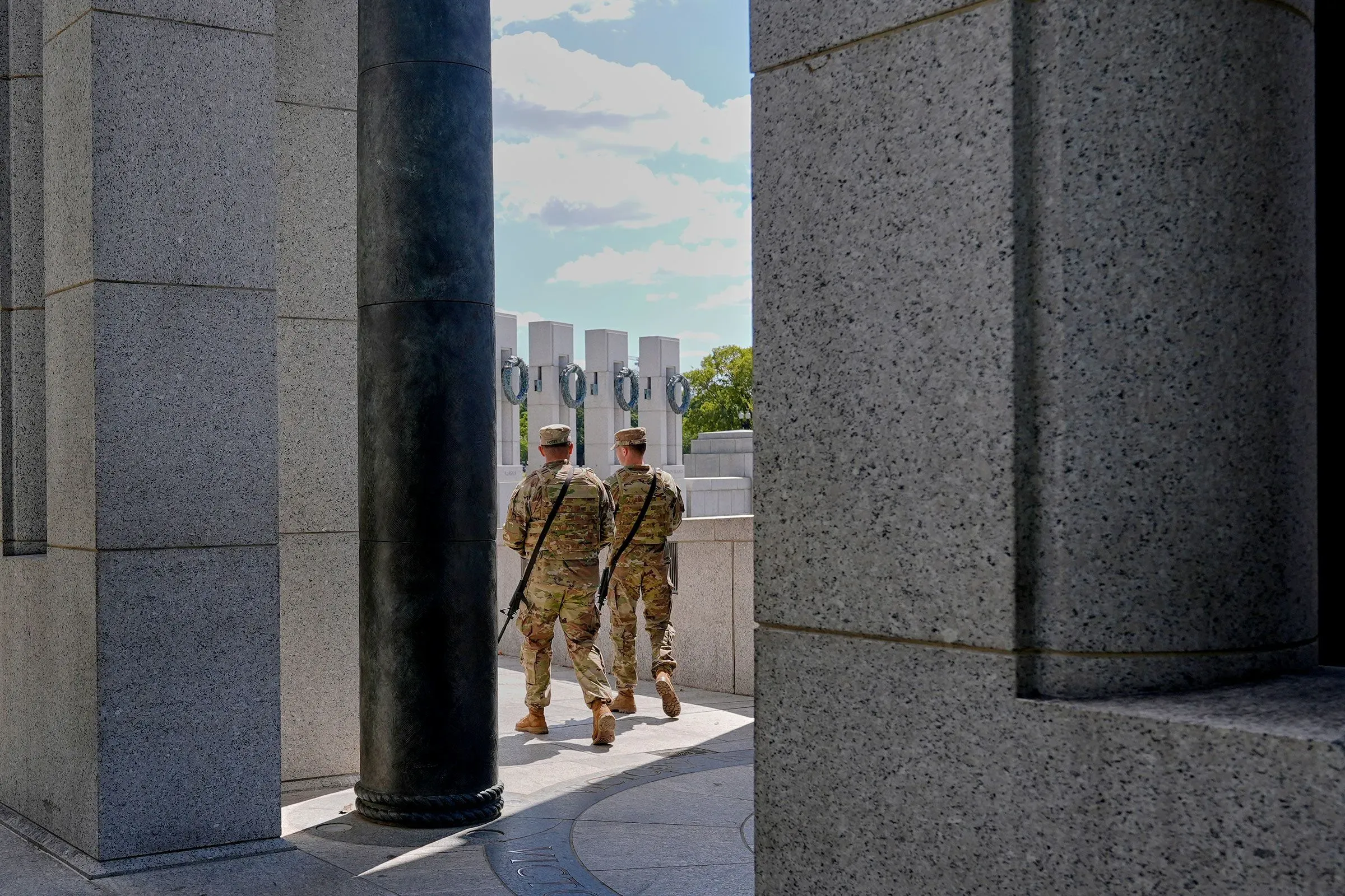 جنود يرتدون زي الجيش الأمريكي يسيرون بين أعمدة معمارية في موقع حكومي، يعكسون النقاش حول استخدام القوات في إنفاذ القانون.