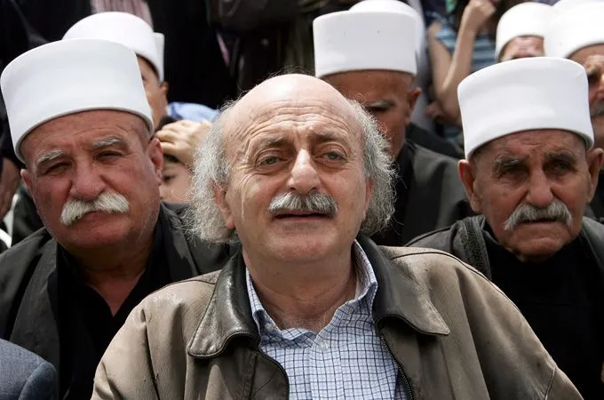 شخصيات درزية في تجمع سياسي، يتوسطهم رجل ذو لحية وشعر أبيض، يرتدون قبعات بيضاء، يعكسون التنوع السياسي في لبنان.