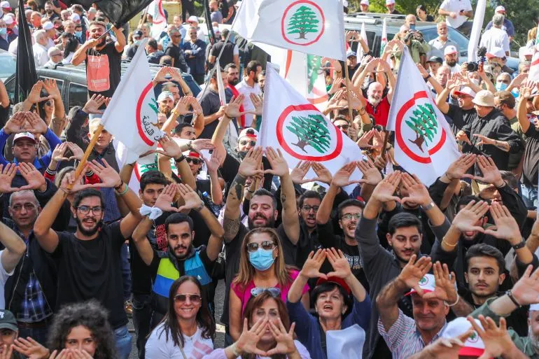تجمع حشود من أنصار القوات اللبنانية في مظاهرة، يحملون الأعلام ويؤدون إشارات تعبيرية تعكس دعمهم للحزب في سياق الصراع السياسي اللبناني.