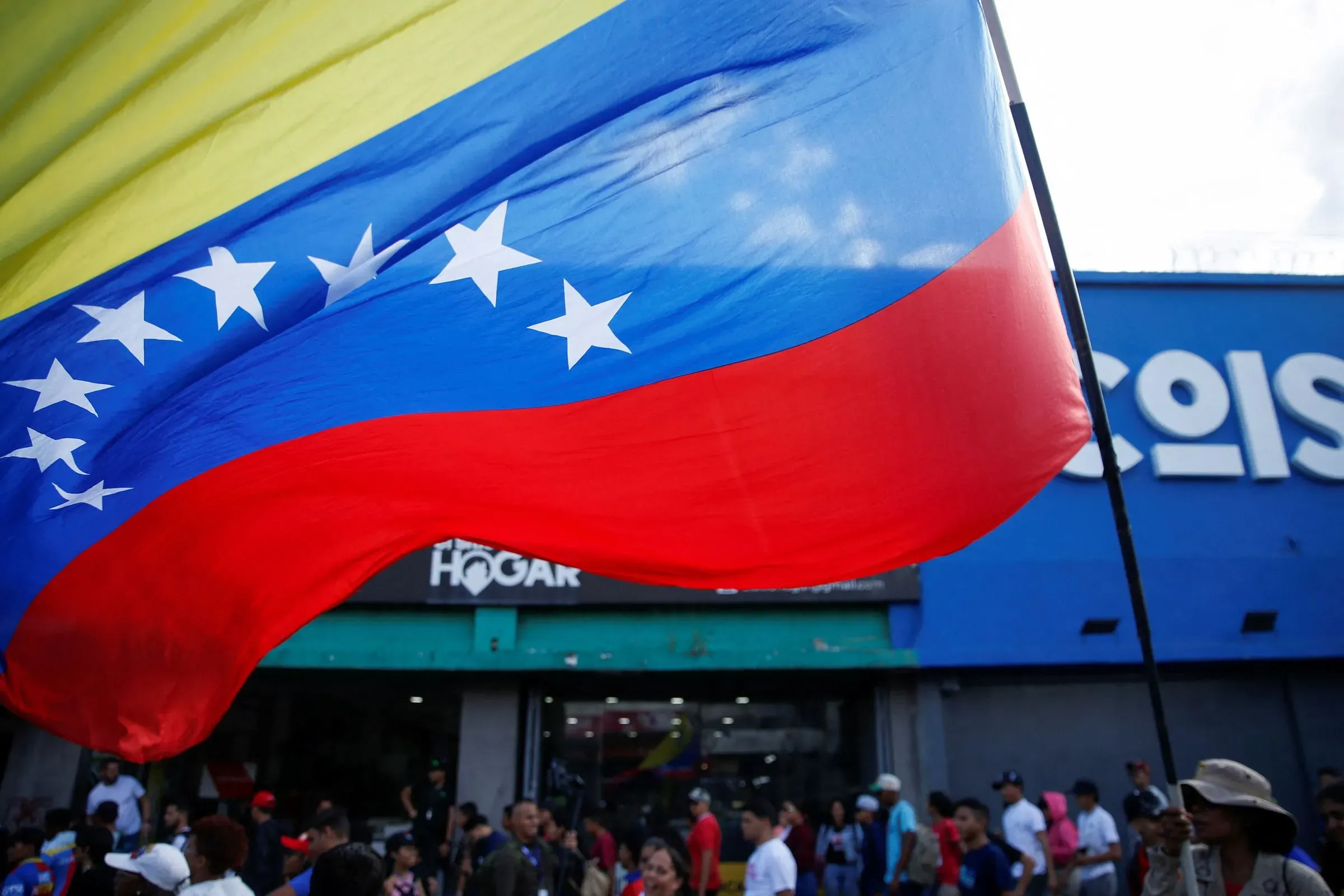 علم فنزويلا يرفرف في تجمع شعبي، حيث يعكس الأمل في التغيير السياسي والاستقرار في البلاد وسط الأزمات الحالية.