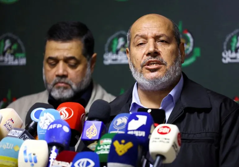 خليل الحية يتحدث في مؤتمر صحفي بعد انتخابه رئيساً لحركة Hamas، مع وجود ميكروفونات وسائل الإعلام المتعددة أمامه.