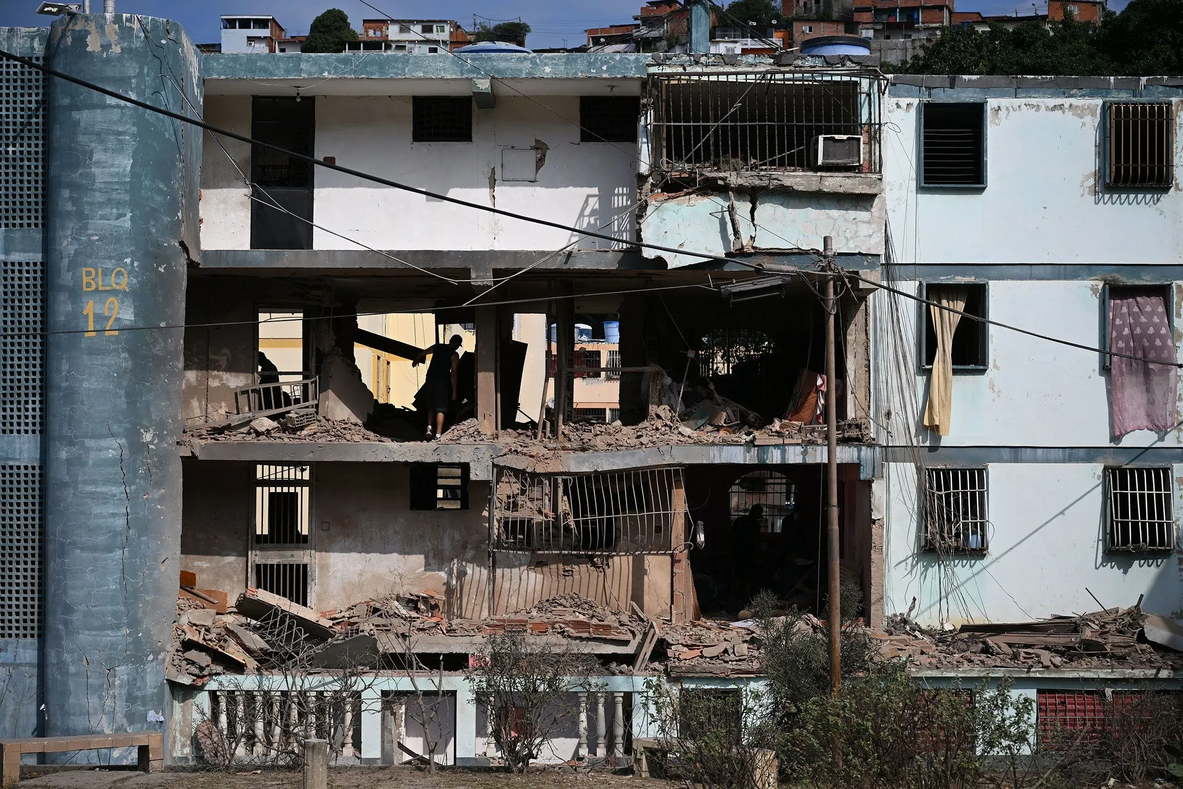 مبنى مدمر في فنزويلا يظهر آثار العنف والصراع، مع وجود شخص يعمل في الموقع، مما يعكس الأوضاع الإنسانية المتدهورة.