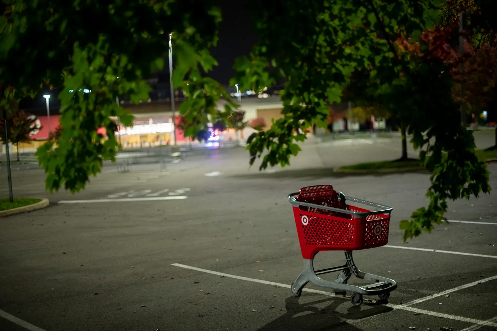 عربة تسوق حمراء متروكة في ساحة انتظار فارغة، تعكس تأثير سرقة المتاجر على تجارة التجزئة بعد الجائحة.