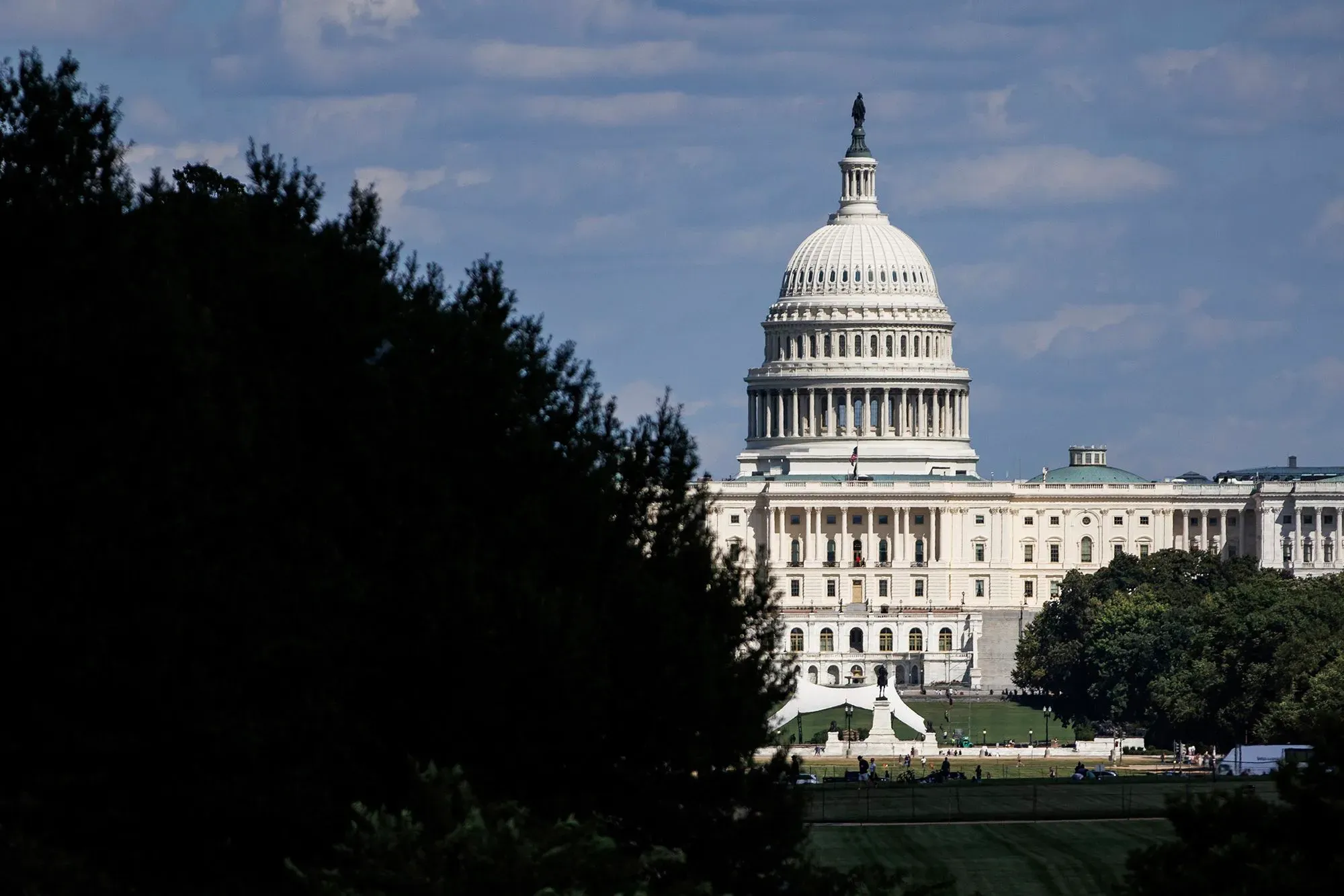 مبنى الكابيتول الأمريكي يظهر في الخلفية مع سماء زرقاء، بينما تبرز الأشجار من الجانبين. الصورة تعكس النقاش حول قضايا السرقة من المتاجر.