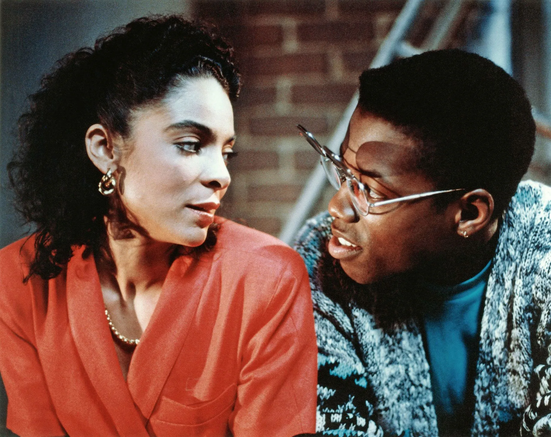 مشهد من مسلسل A Different World يظهر تفاعل بين شخصيتين سوداوين في حرم جامعة Hillman، يعكس قضايا التنوع والهوية السوداء في التعليم العالي.