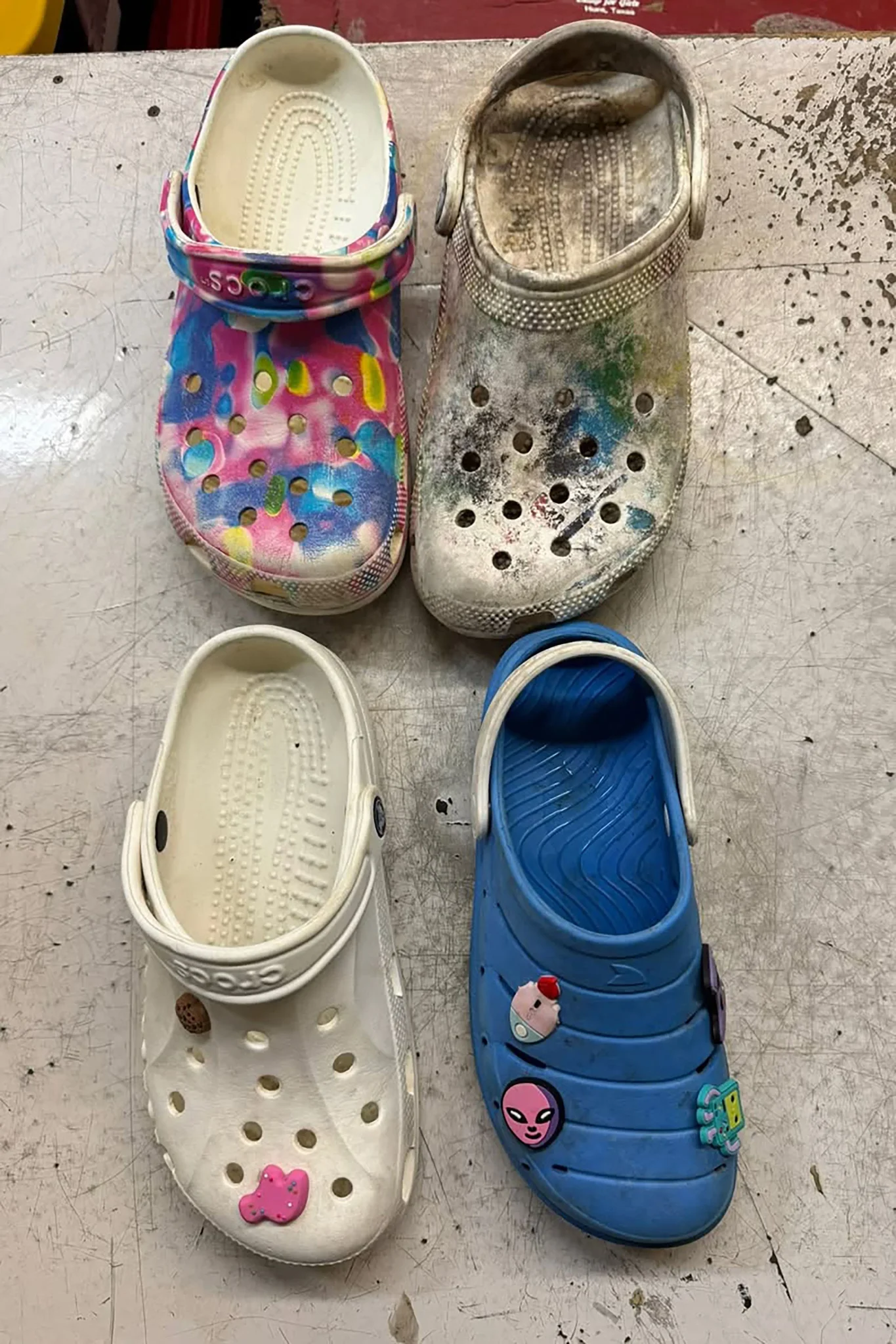 أربعة أحذية Crocs ملونة ومتنوعة بحالة متفاوتة تم العثور عليها بعد فيضان نهر Guadalupe في تكساس، تعكس خسائر وممتلكات الناجين.