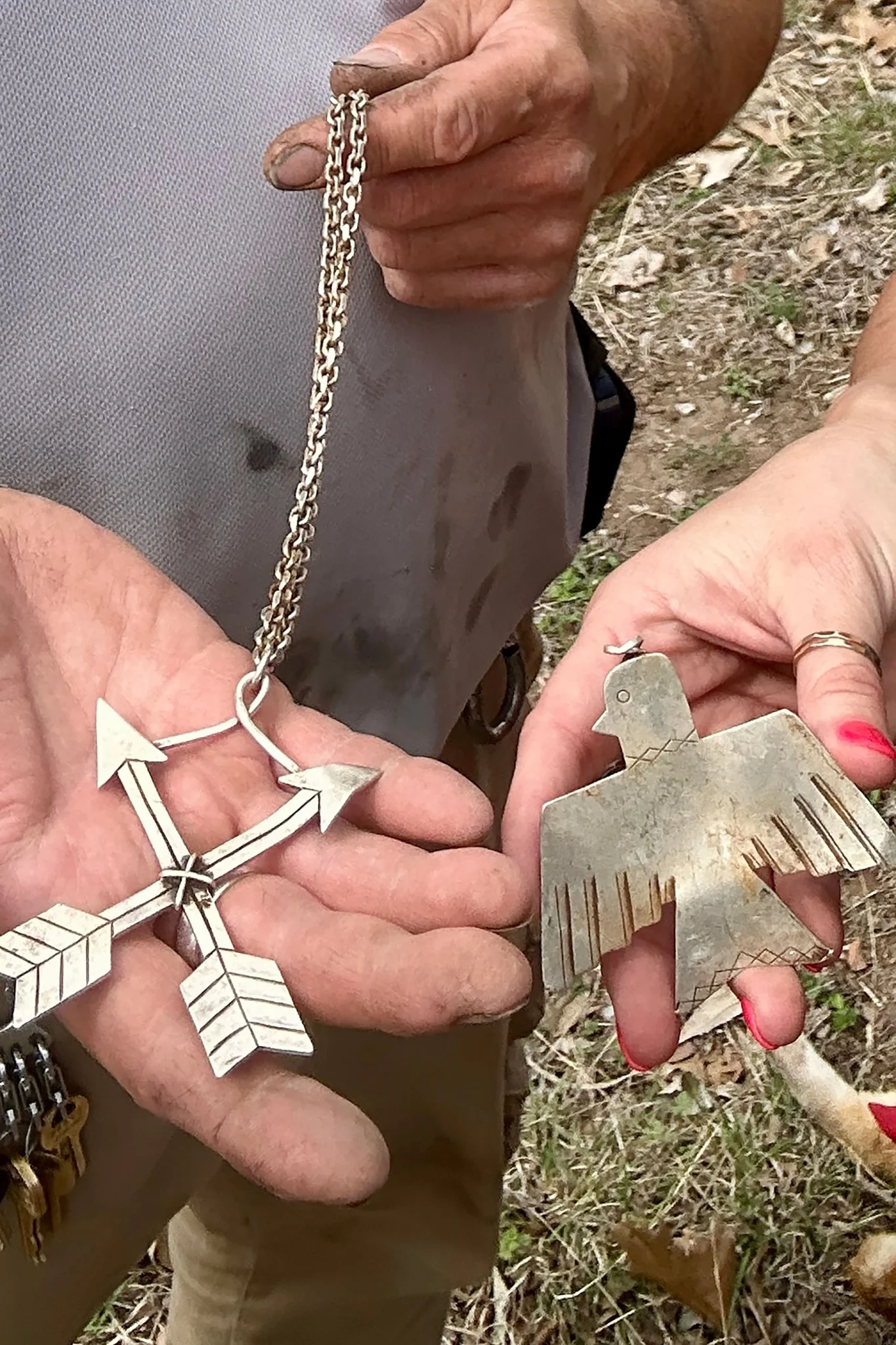 يدان تمسكان بقلادتين فضيتين عثرت عليهما بعد فيضان نهر Guadalupe في تكساس، رمزاً لاستعادة الممتلكات الشخصية للناجين.