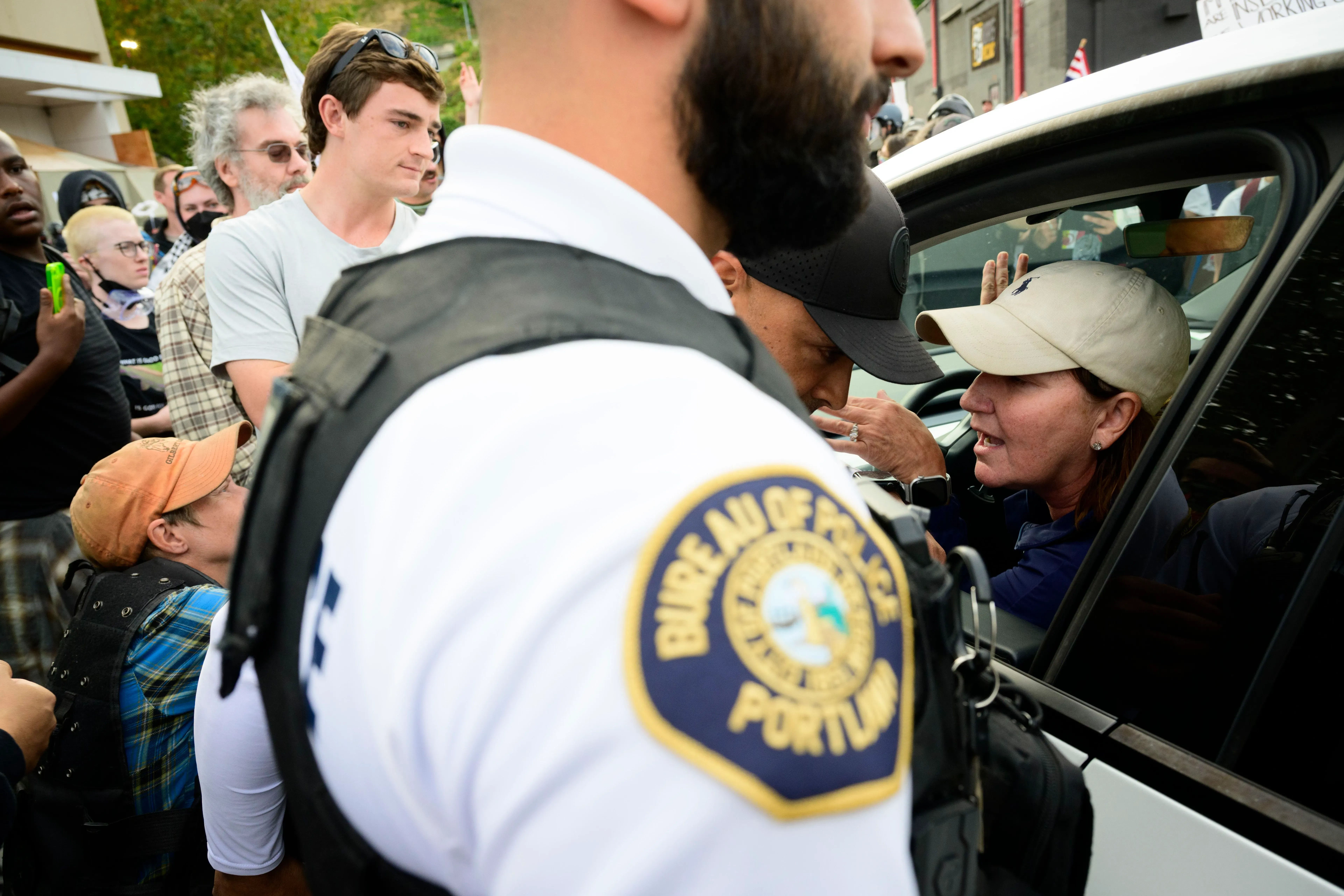 مظاهرة في بورتلاند حيث يتفاعل ضباط إنفاذ القانون مع حشد من المتظاهرين، مع وجود توتر واضح في الأجواء.