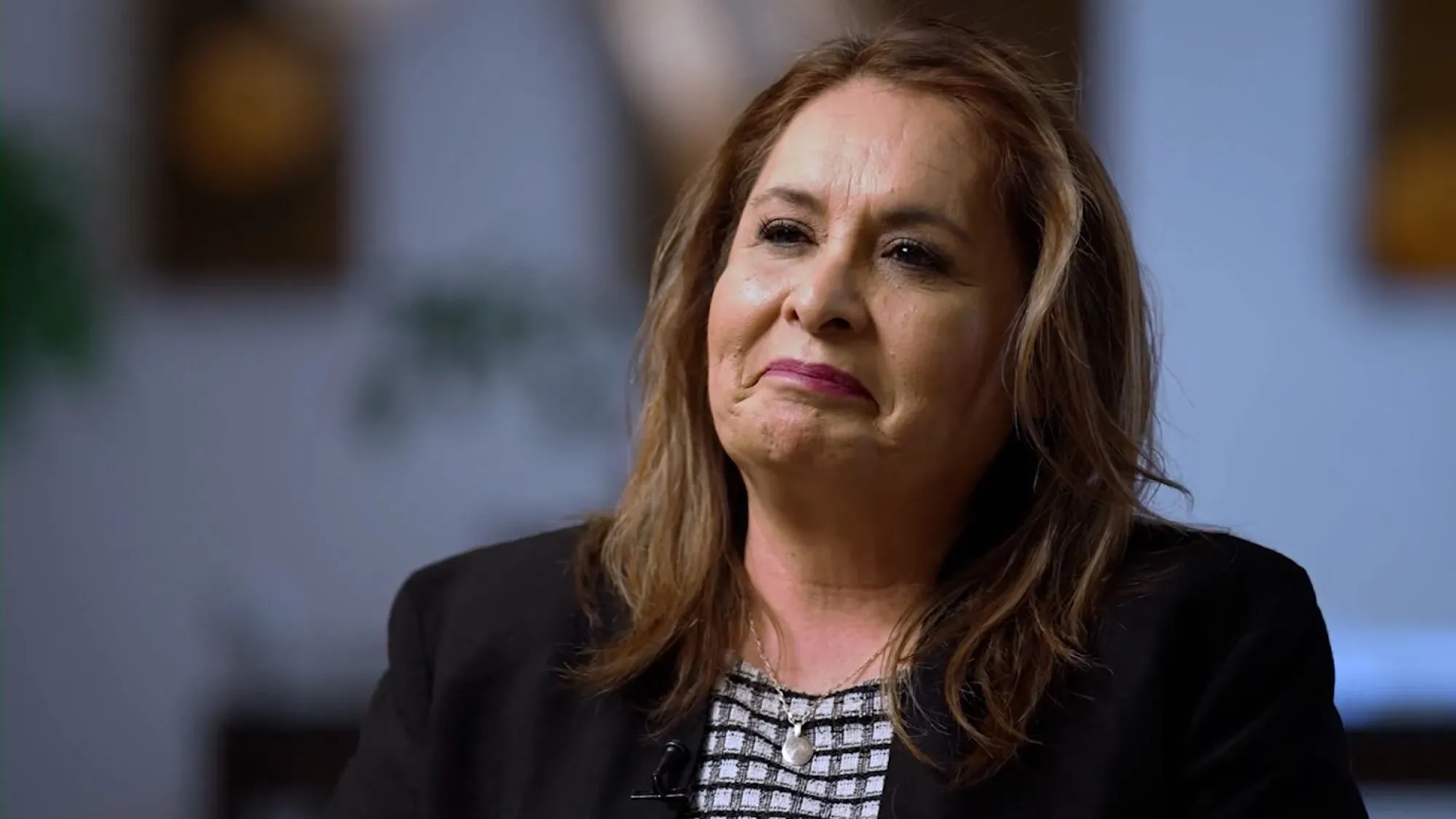 امرأة تتحدث بجدية، تعبر عن مشاعر مختلطة حول الوضع السياسي الحالي وتأثيره على حياتها اليومية.