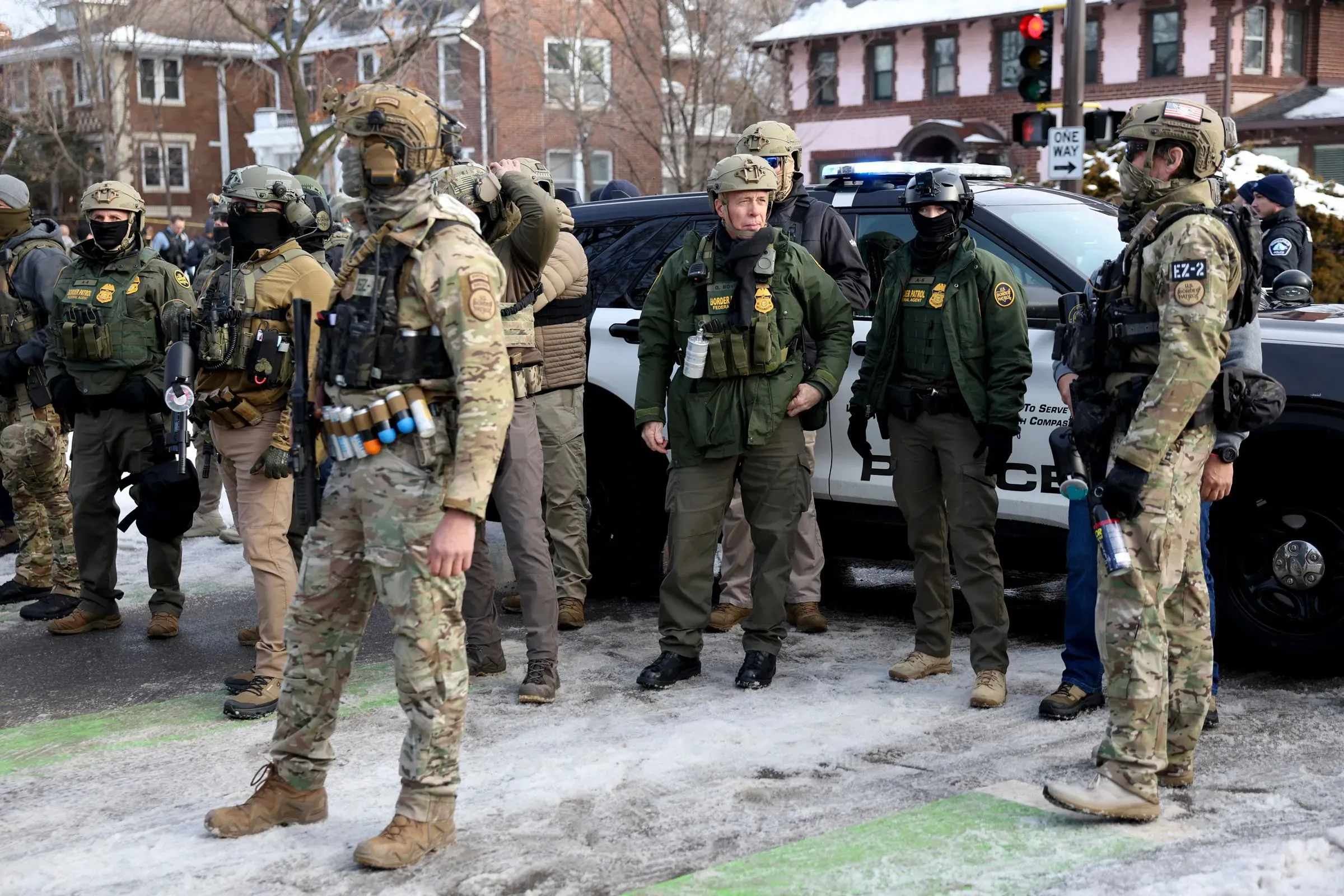 مجموعة من ضباط إنفاذ قوانين الهجرة والجمارك في مينيابوليس، يرتدون زيًا عسكريًا ويستعدون لتنفيذ عملية في منطقة حضرية.