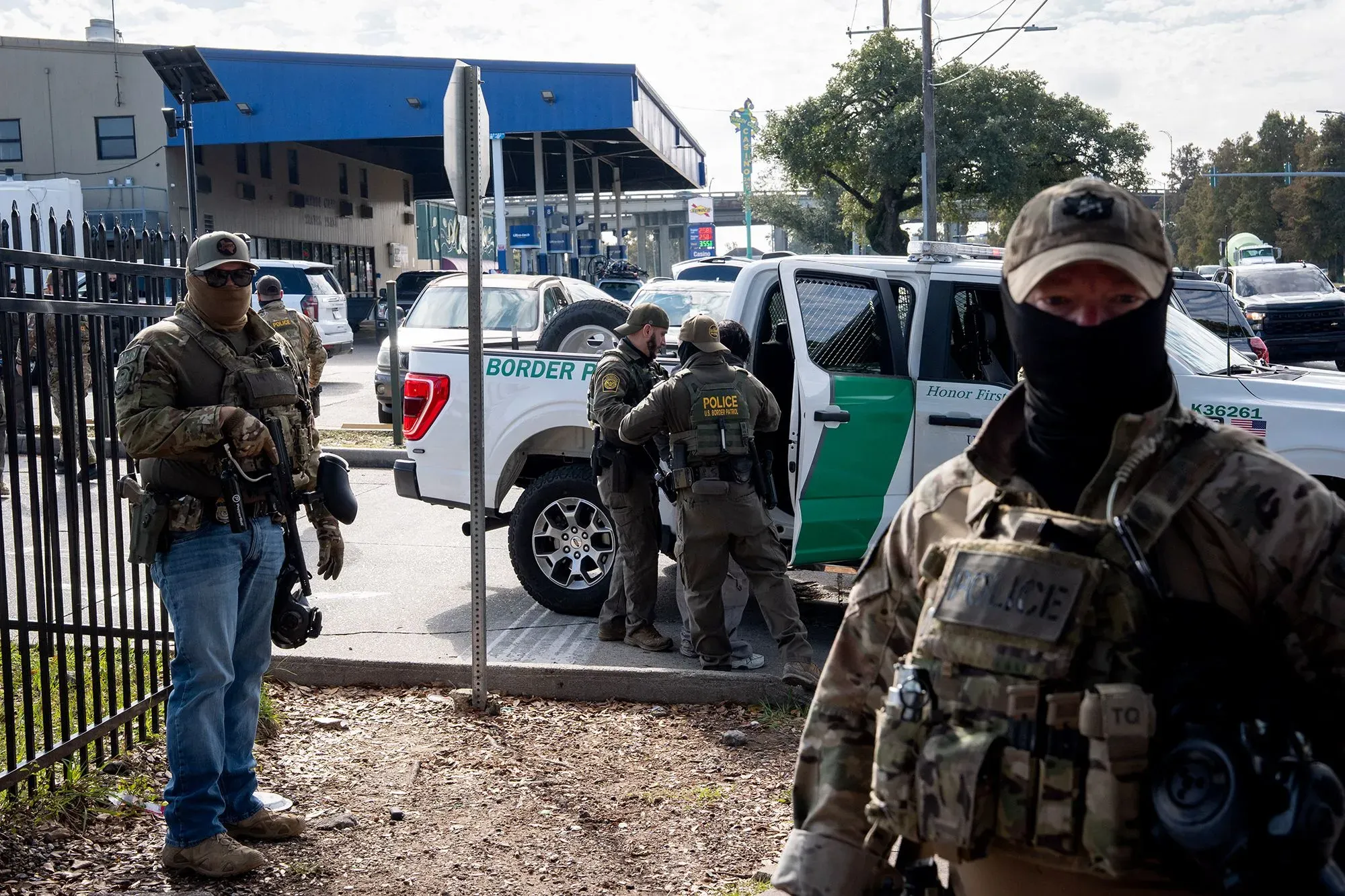 تظهر الصورة مجموعة من العملاء الفيدراليين يرتدون زيًا عسكريًا، يتجمعون حول مركبة تابعة لوكالة إنفاذ قوانين الهجرة.