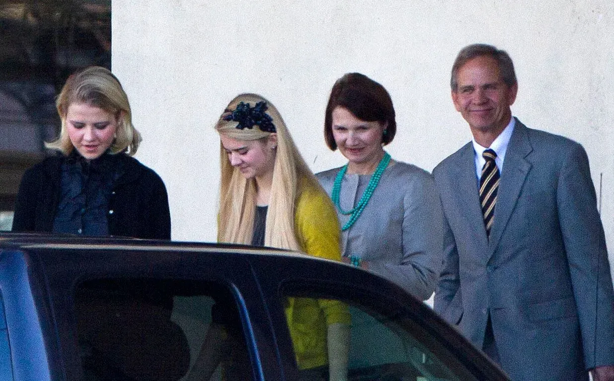 إليزابيث سمارت مع عائلتها، يظهرون وهم يتجهون نحو سيارة، مع تعبيرات مختلطة تشير إلى الدعم والترابط الأسري بعد تجربتها المؤلمة.