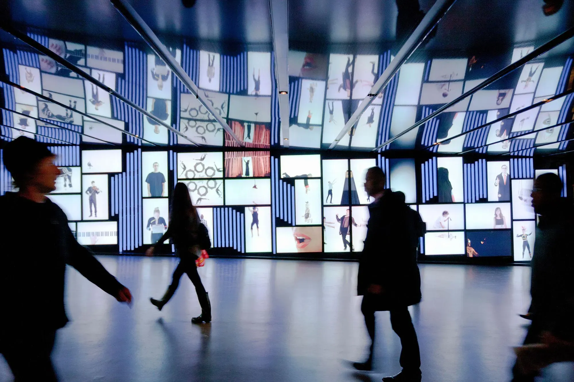 ممر تحت الأرض في تورونتو، حيث يسير الناس بين شاشات عرض كبيرة تعرض محتوى متنوع، مما يعكس الحياة النابضة في المدينة.