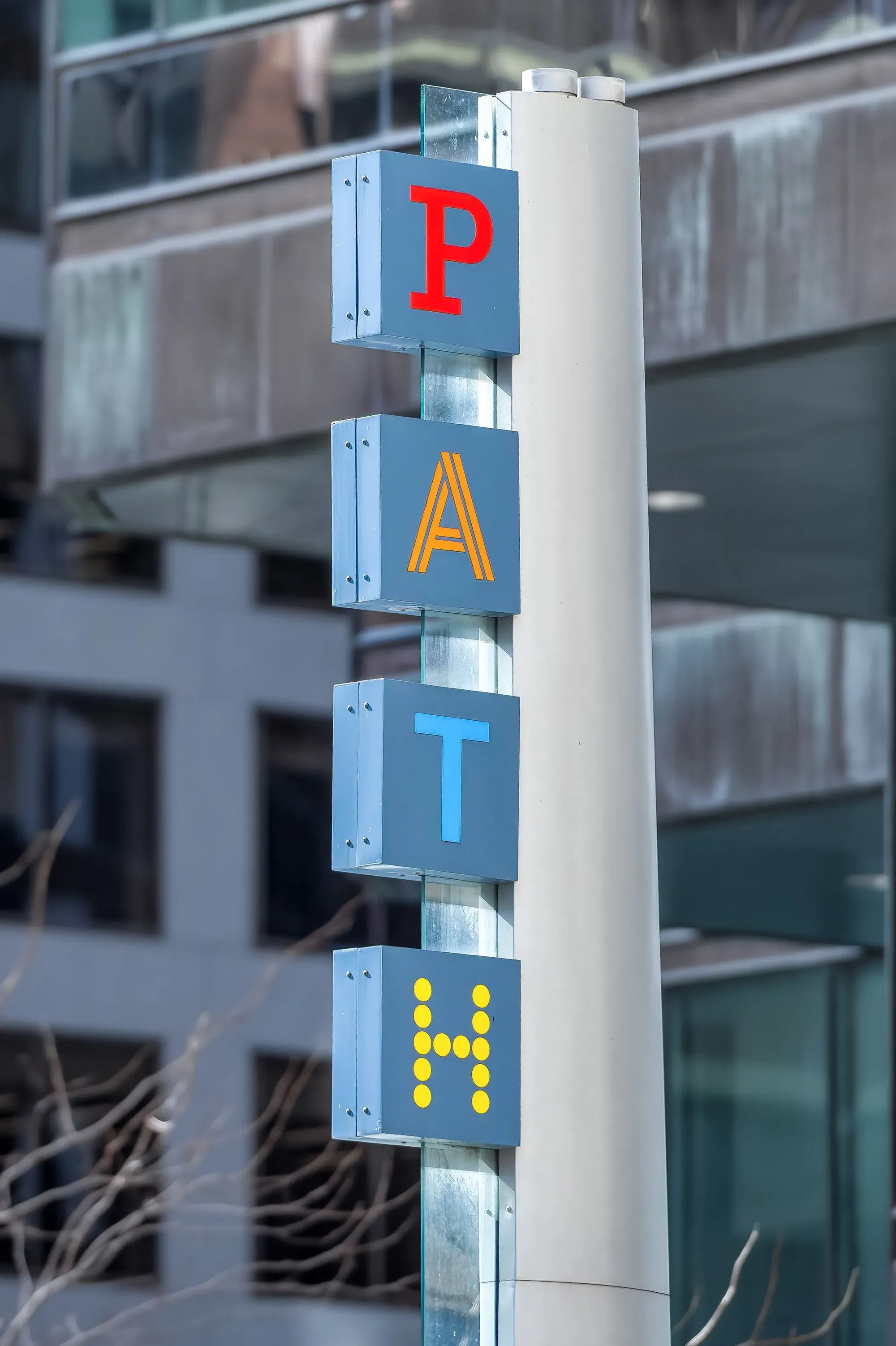 علامة تشير إلى شبكة PATH تحت الأرض في تورونتو، مع حروف ملونة تمثل الاسم، في خلفية حضرية معمارية.