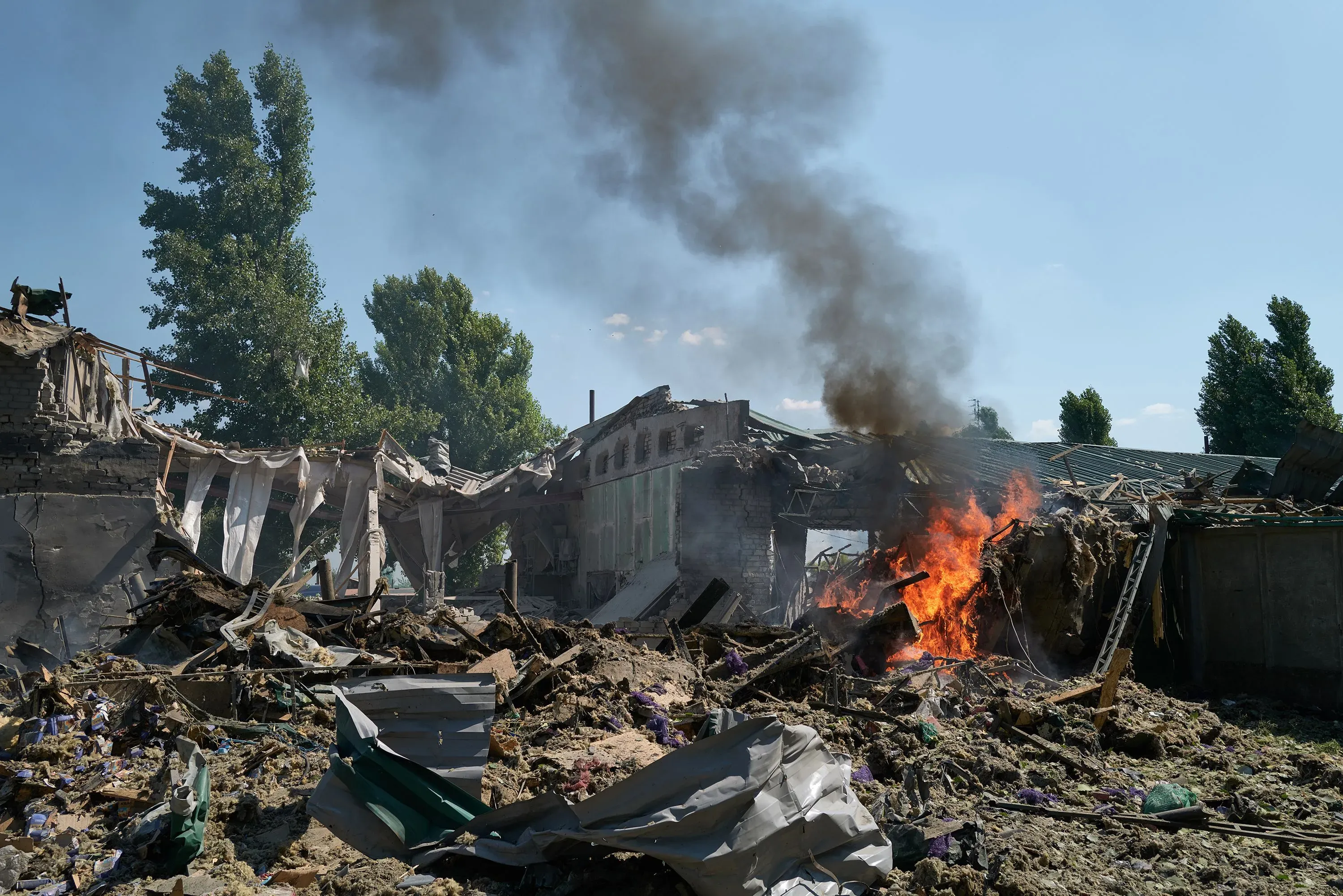 دمار كبير في مبنى، مع تصاعد الدخان والنيران، يعكس آثار النزاع في أوكرانيا وتأثيره على المدنيين.