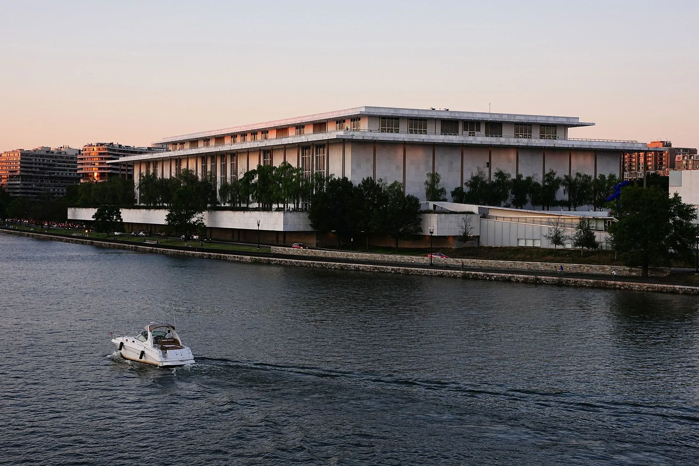 مركز كينيدي للفنون المسرحية في واشنطن، يظهر بجوار نهر مع قارب يبحر، يستعد لاستضافة حفل تكريم للموسيقيين والممثلين.