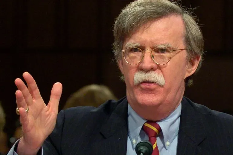 جون بولتون يتحدث بجدية، مع التركيز على تفاصيل اتهاماته بتبادل معلومات حكومية سرية، مما يعكس دوره كمستشار أمني مثير للجدل.