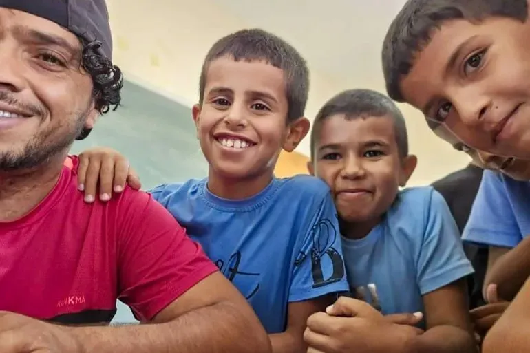 عودة الهذالين مع ثلاثة أطفال مبتسمين، في لحظة تعكس حبه وعلاقته القوية معهم، في سياق مقاومة الاحتلال في مسافر يطا.
