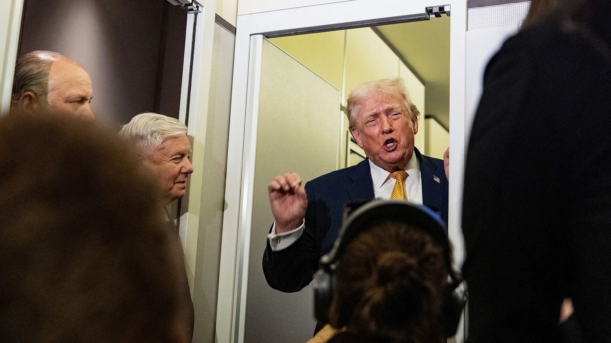 تصريح لترامب خلال حدث عام، حيث يتحدث بحماسة عن غرينلاند وأهميتها الاستراتيجية، مع وجود أشخاص آخرين في الخلفية.