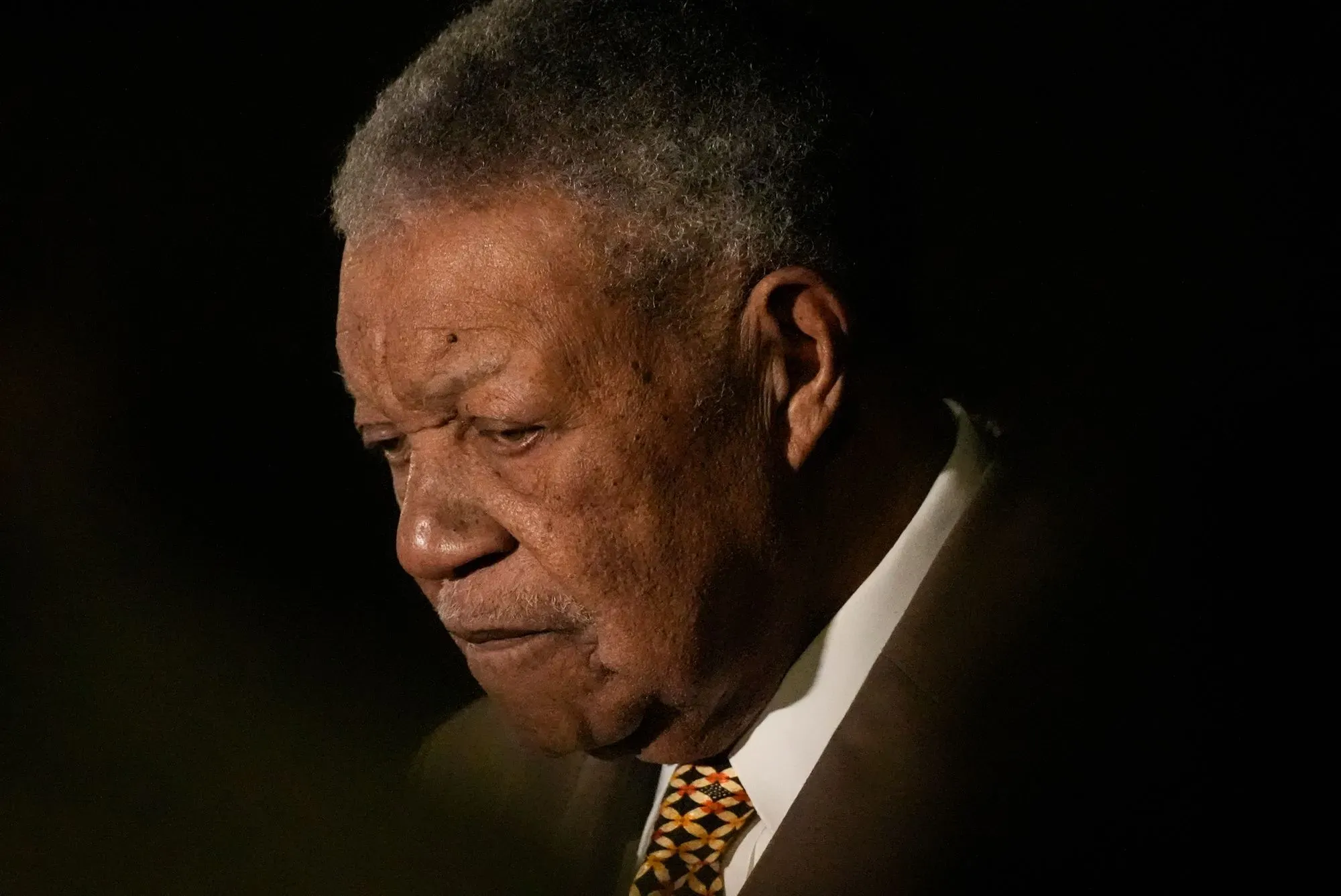 صورة تظهر رجل مسن يبدو عميق التفكير، مع إضاءة خافتة تبرز ملامح وجهه. تعكس الصورة أجواء جدية وتوتر مرتبطة بمناقشات حول الانتخابات.