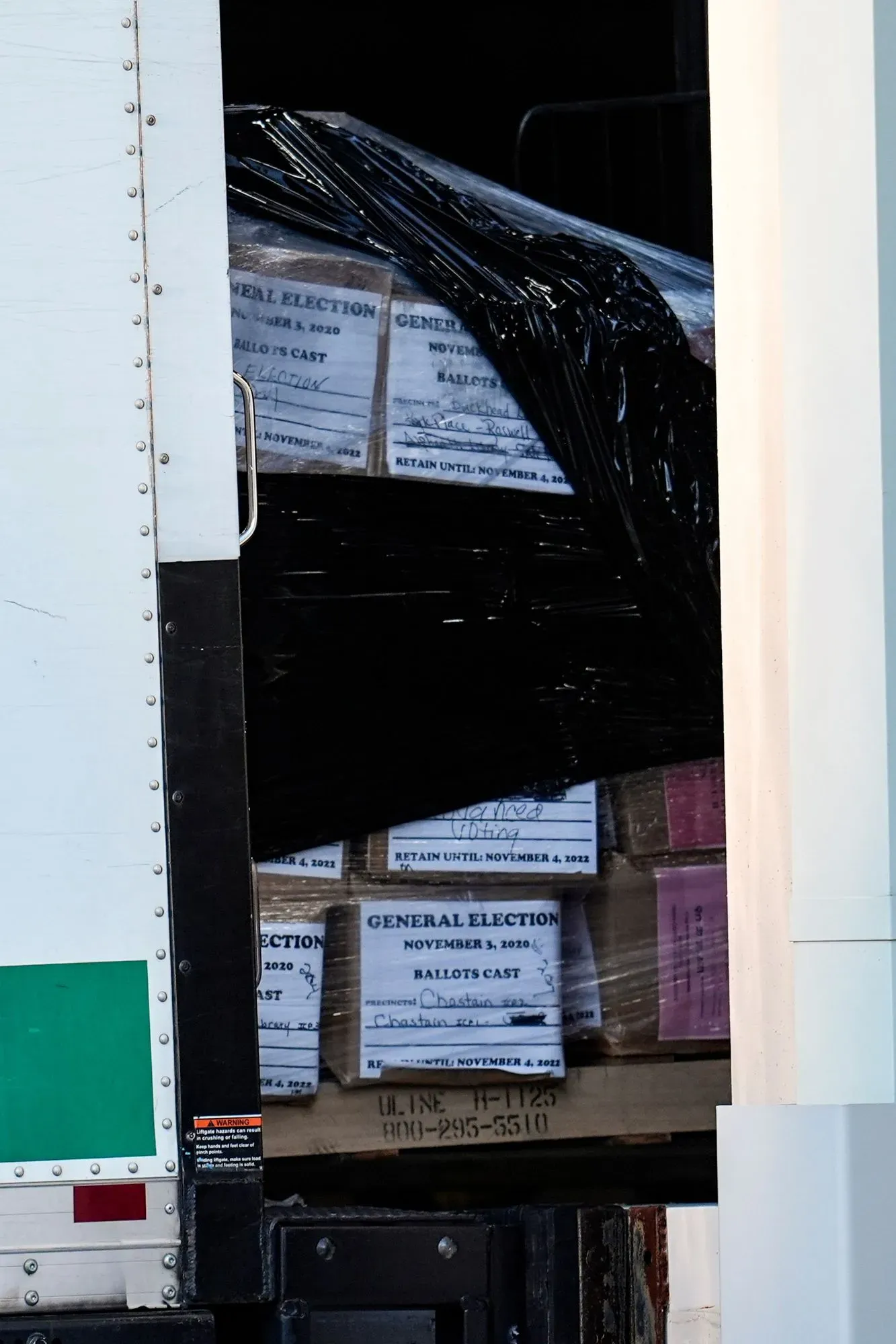 صناديق اقتراع مختومة من انتخابات 2020 تُنقل في شاحنة، مما يعكس التدقيق المستمر في نتائج الانتخابات وتأثيرها على الانتخابات المقبلة.