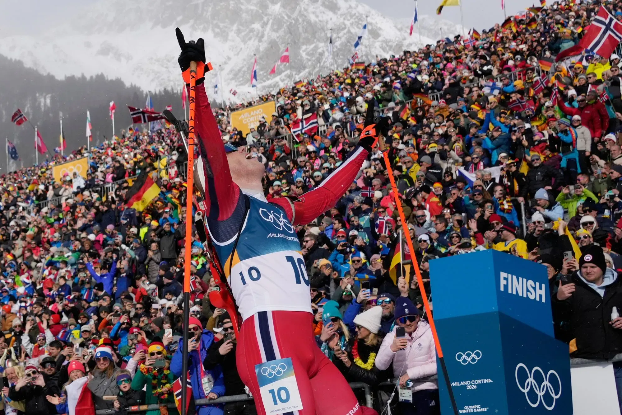 رياضي نرويجي يحتفل بفوزه في سباق التزلج، وسط حشد كبير من الجماهير في الألعاب الأولمبية الشتوية، مع العلم النرويجي في الخلفية.