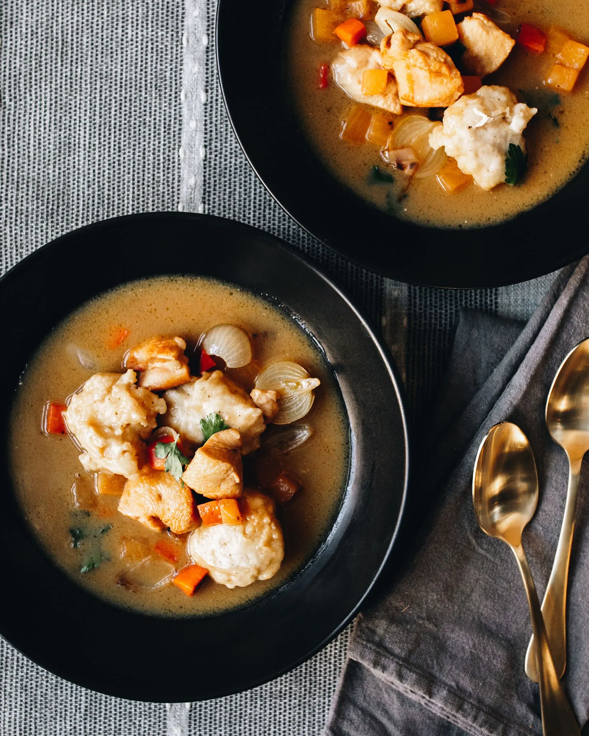 حساء الدجاج والزلابية في وعاء أسود، مع قطع دجاج وخضروات، يعكس وصفة جد الشيف جافين كايسن التقليدية.