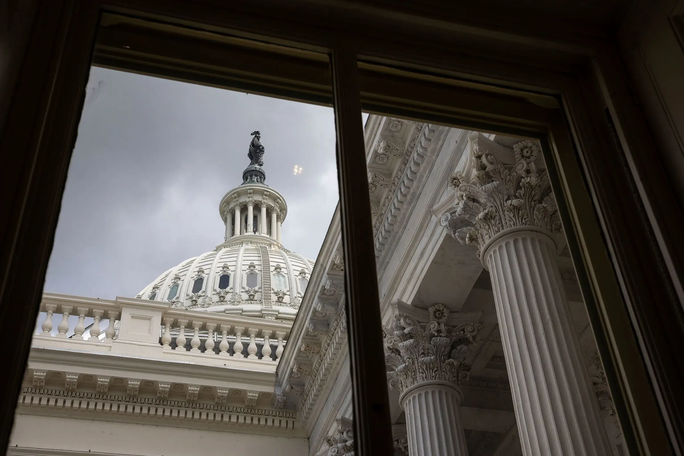 نظرة من داخل مبنى حكومي على قبة الكابيتول، مع أعمدة مزخرفة وسحاب رمادي في السماء، تعكس أهمية القضايا البيئية والسياسية.