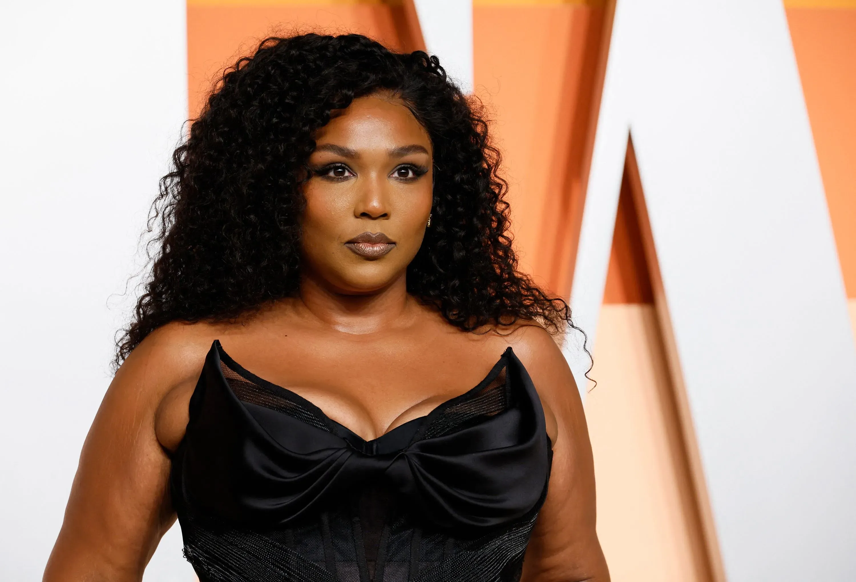 مغنية ترتدي فستانًا أسودًا أنيقًا، تظهر بإطلالة واثقة، في حدث عام، مما يعكس موضوعات التنوع والجمال في الثقافة المعاصرة.