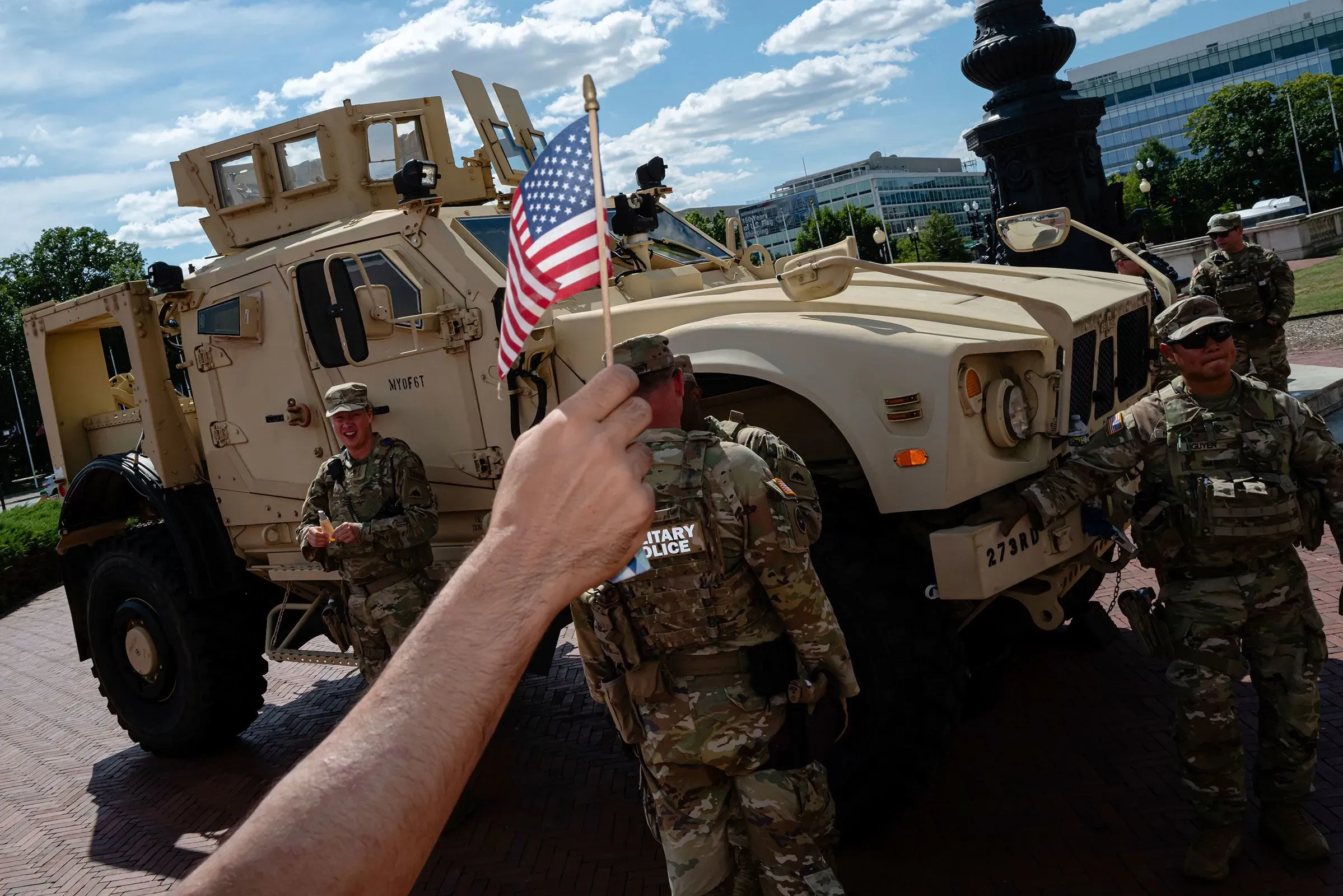 جنود من الحرس الوطني الأمريكي يقفون بجوار مركبة عسكرية، يحمل أحدهم علم الولايات المتحدة، في موقع مهام بالعاصمة واشنطن.