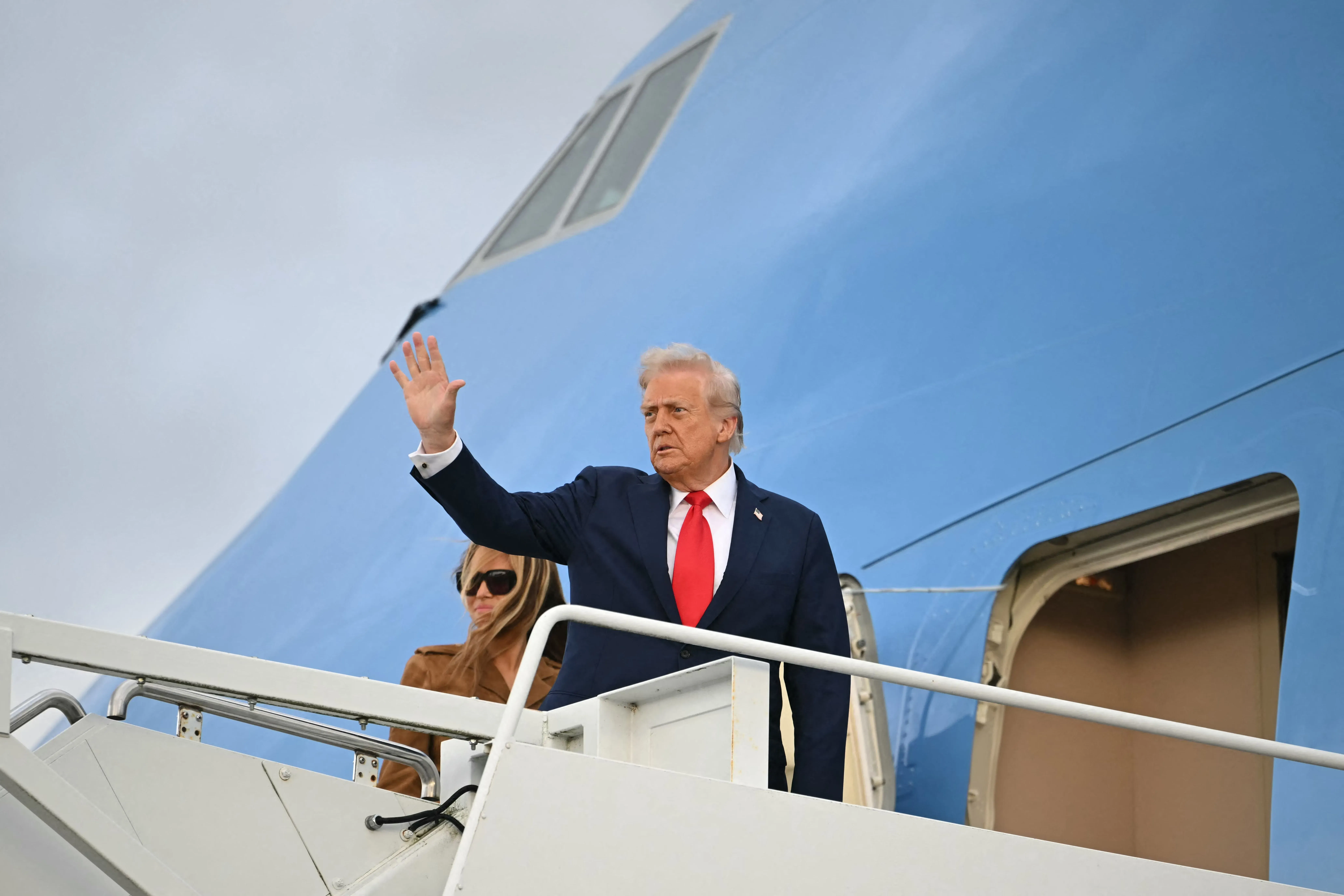 ترامب يلوح بيده أثناء صعوده إلى الطائرة الرئاسية، مع وجود شخص آخر بجانبه، في سياق حديثه عن تأثير الإعلام عليه.