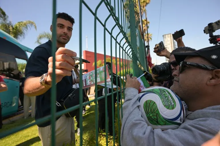لاعب كرة قدم يوقع على كرة أمام حشد من المعجبين، مع وجود كاميرات تلتقط اللحظة، في أجواء حماسية خلال كأس العالم 2026.