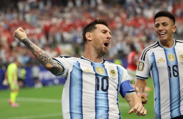 ميسي يحتفل بتسجيل هدف في مباراة كأس العالم، مع زميله في الفريق، مع أجواء حماسية في الملعب.