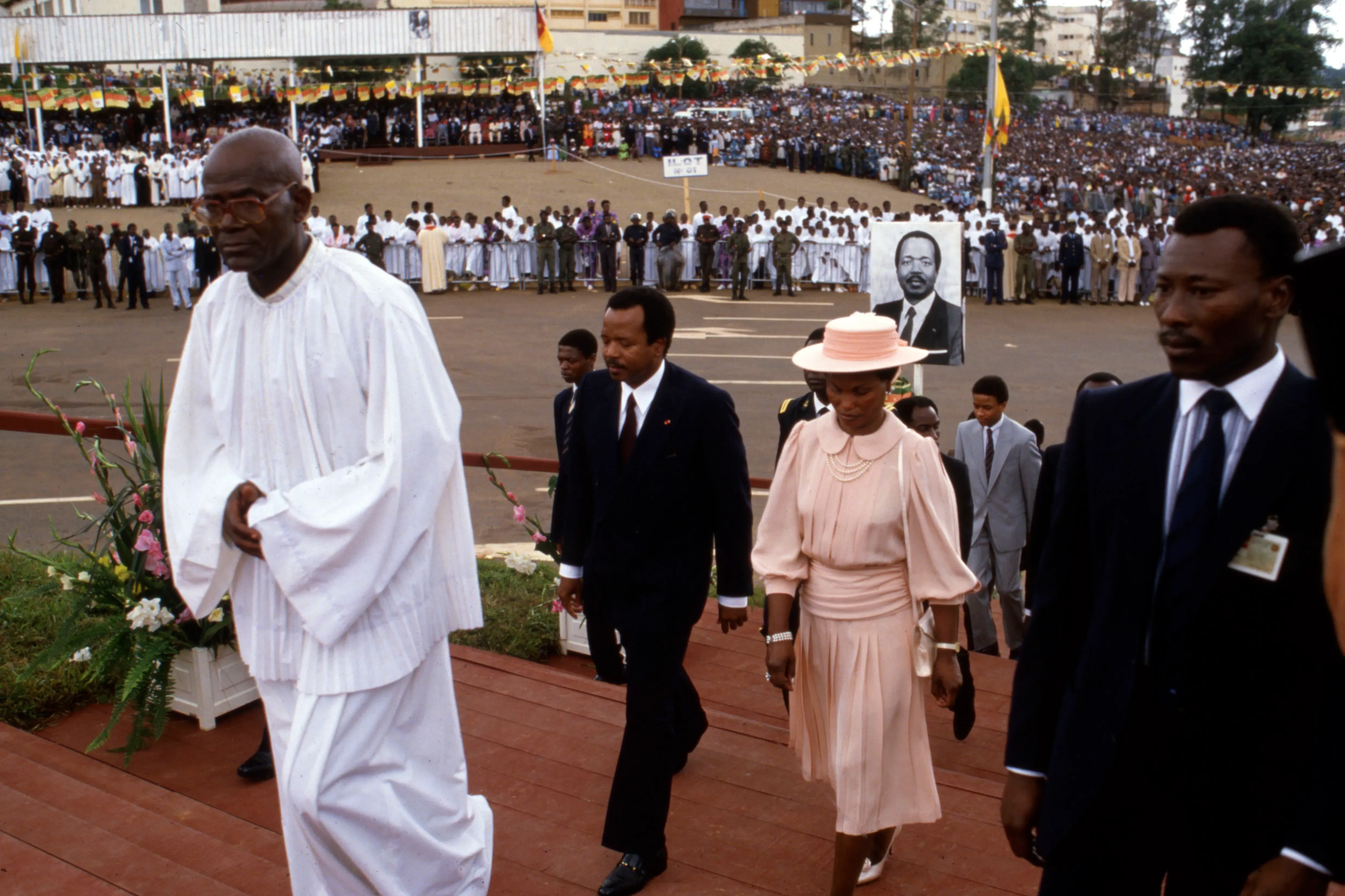 صورة تاريخية تظهر الرئيس الكاميروني بول بيا مع شخصيات سياسية أخرى خلال حدث رسمي، وسط حشد كبير من المواطنين.