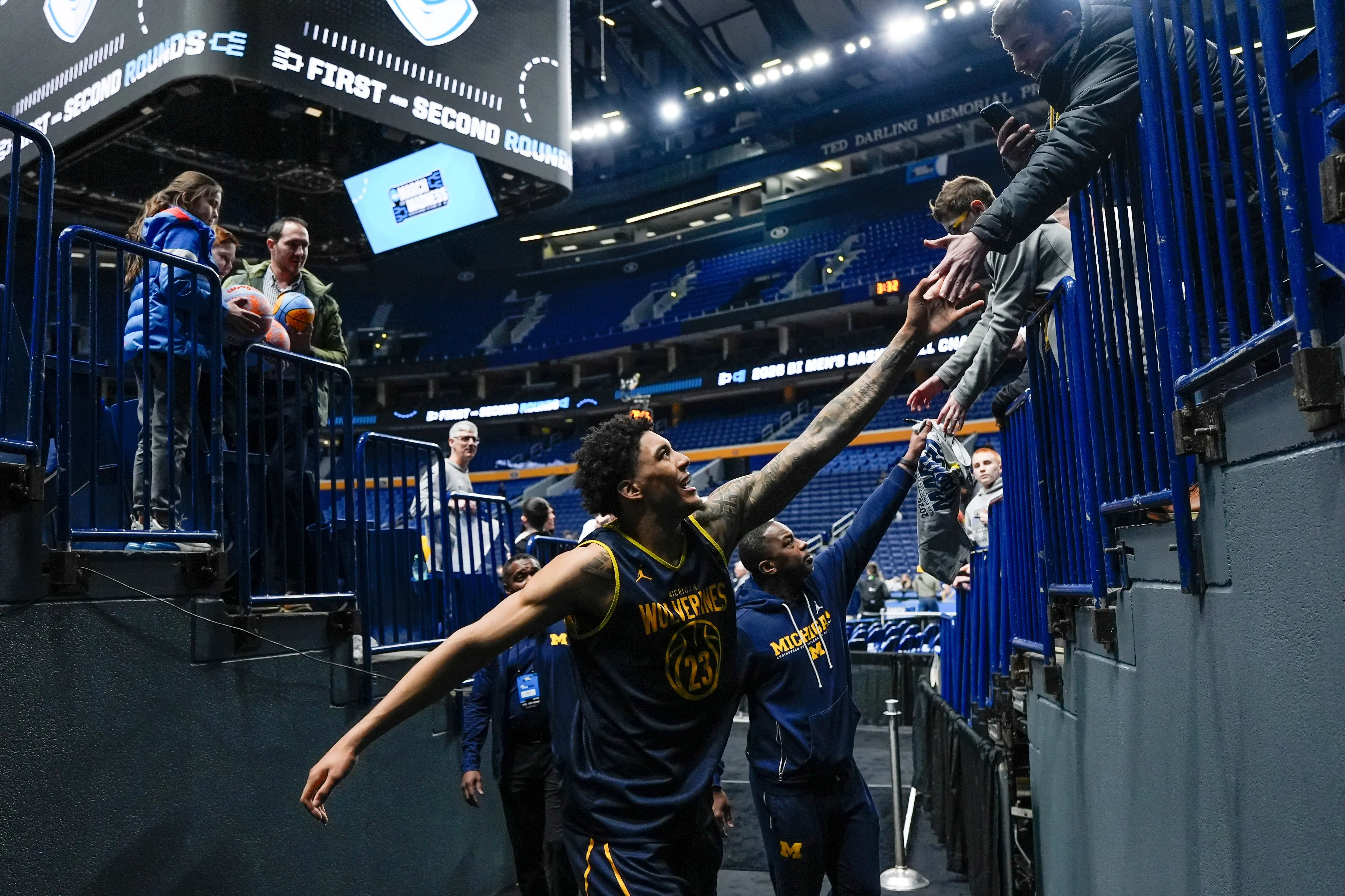 لاعب كرة السلة ياكسيل ليندبورغ يحيي المشجعين بعد مباراة، بينما يظهر خلفه زملاؤه في الفريق في أجواء حماسية.