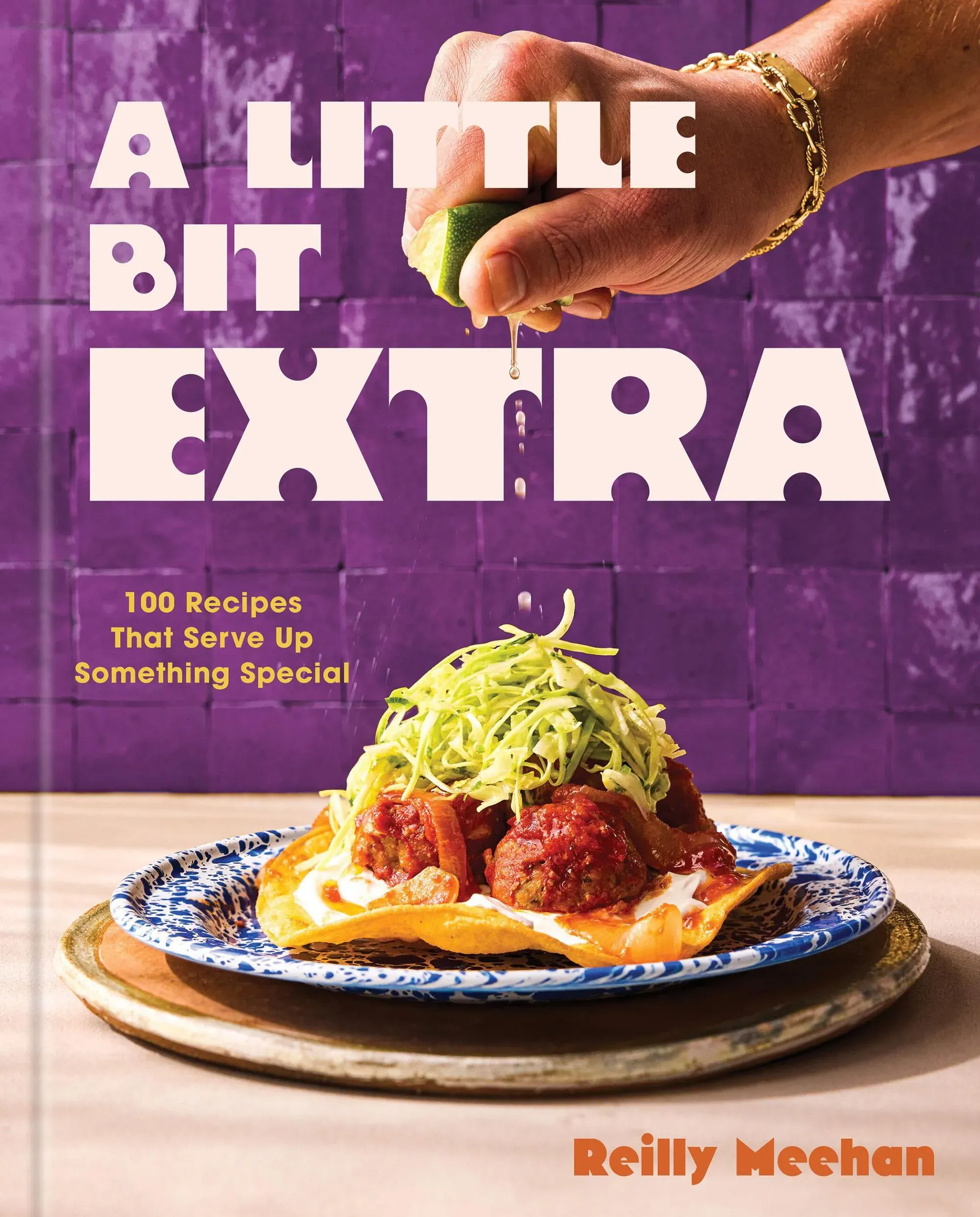 غلاف كتاب "A Little Bit Extra" لريلي ميهان، يظهر طبق لذيذ مع كرات اللحم، صلصة، وشرائح من الكرنب، مع خلفية ملونة.