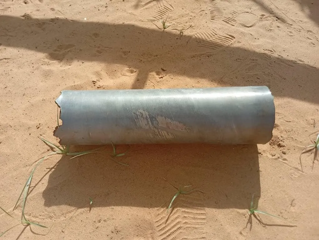 جزء من حطام طائرة مسيّرة على أرض رملية في مدينة الأبيض السودانية، يعكس تأثير النزاع المسلح واستخدام الطائرات المسيّرة في الحرب.