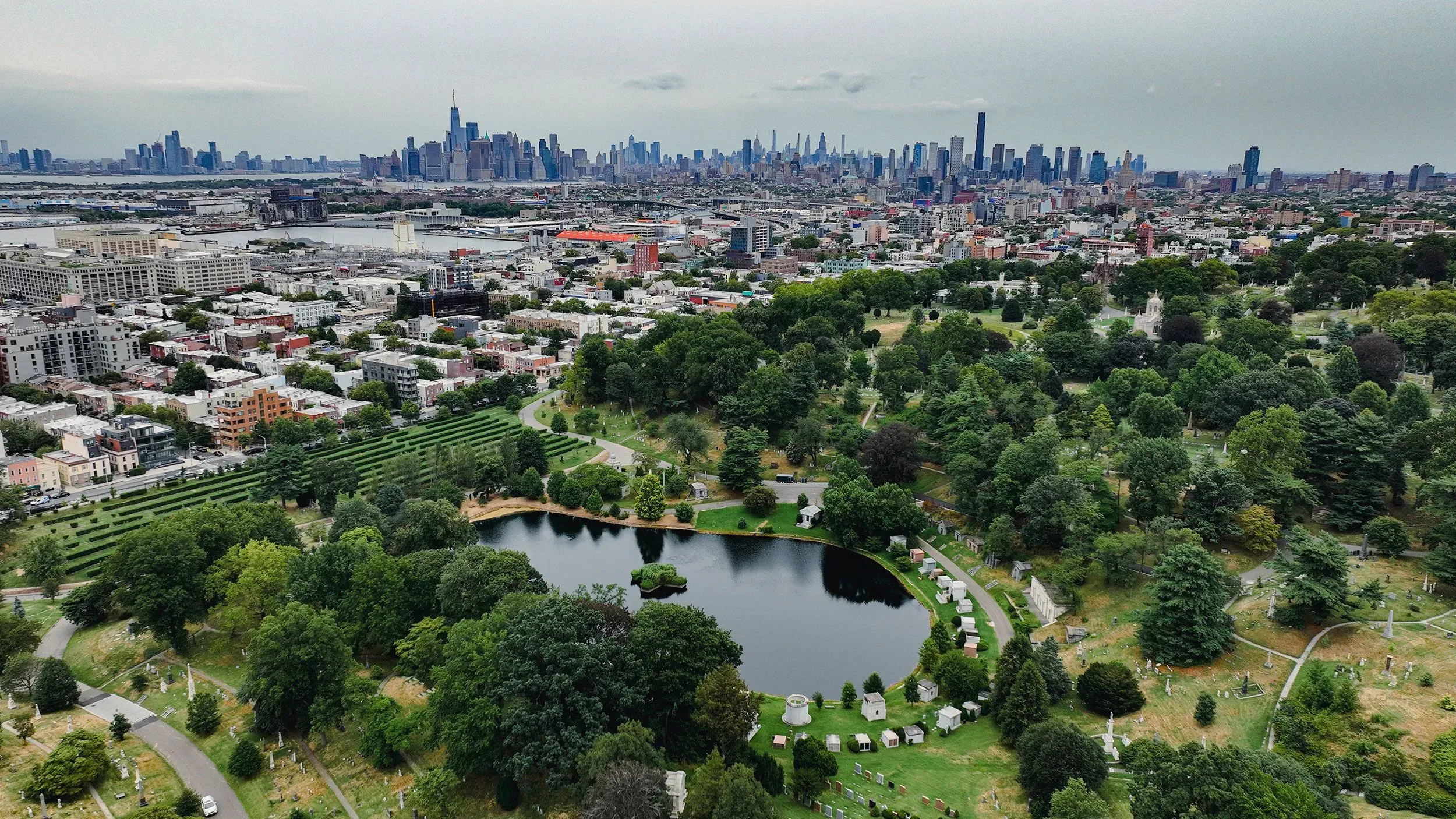 منظر جوي لمدينة نيويورك يظهر الحدائق والمساحات الخضراء مع أفق المدينة في الخلفية، مما يعكس التحديات البيئية للنقل الجماعي.