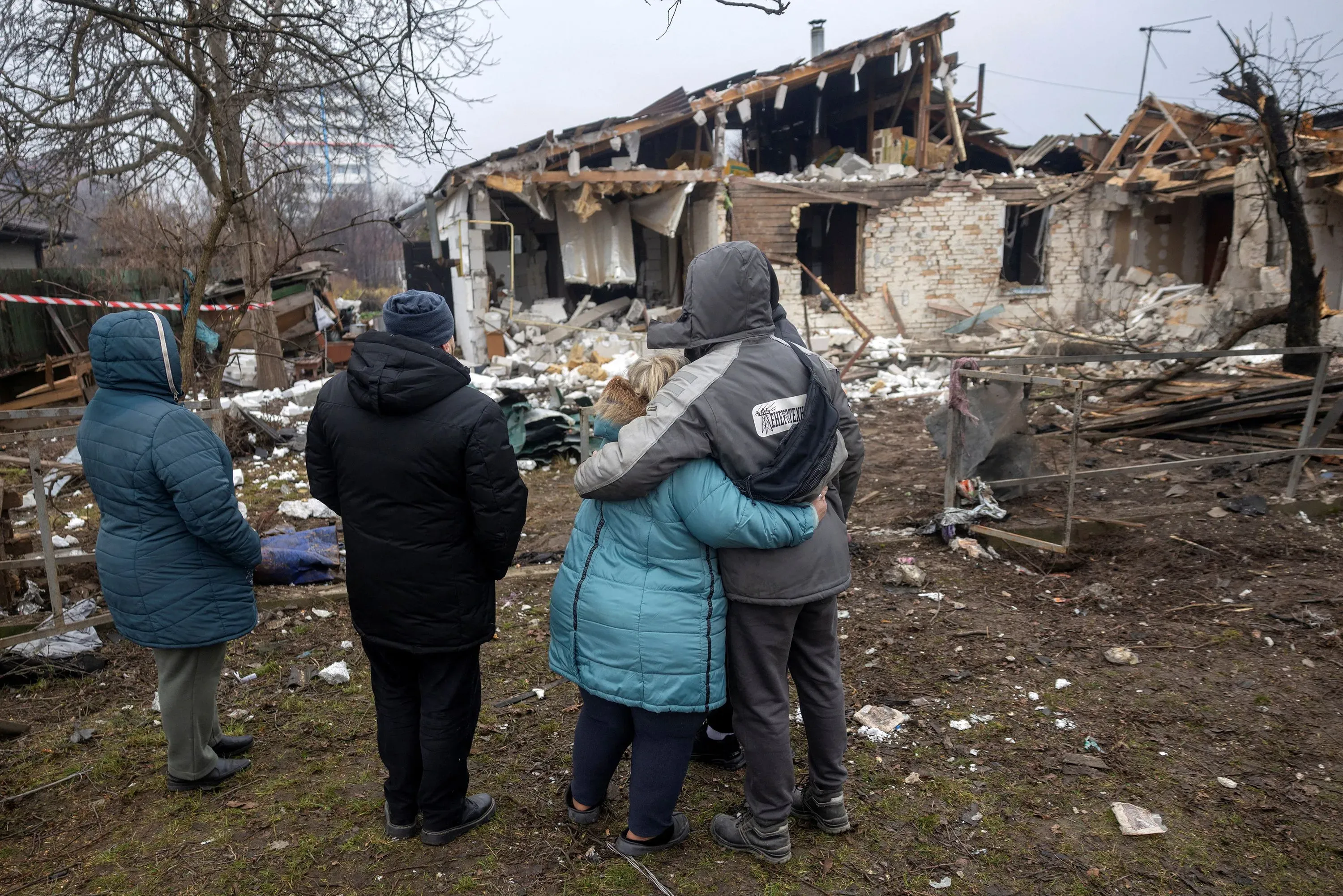 أفراد عائلة يقفون في مواجهة منزل مدمر بفعل الحرب، يعكس تأثير الصراع على المدنيين في أوكرانيا.