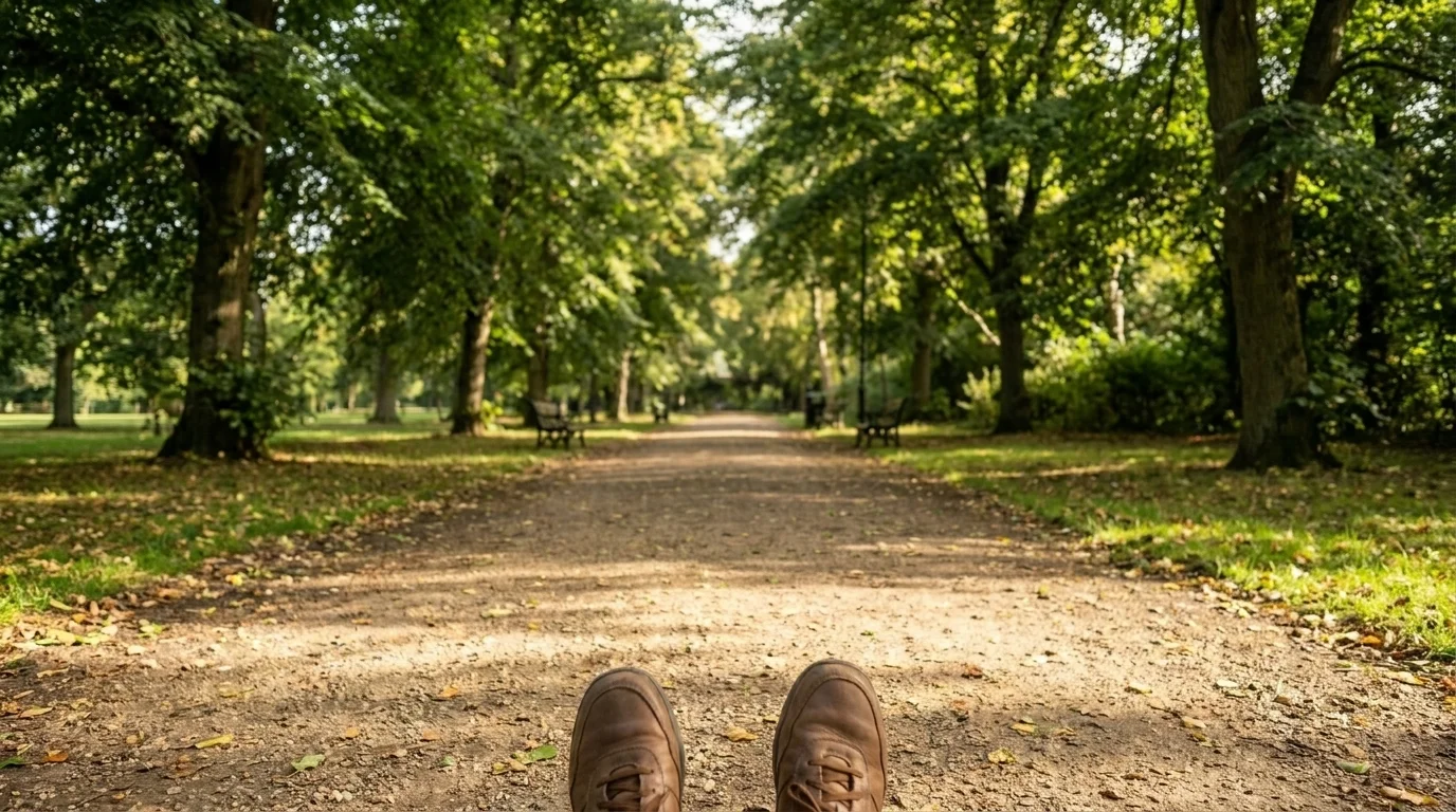 First-person view down a quiet, open park path framed by greenery in soft daylight, the route stretching calmly ahead