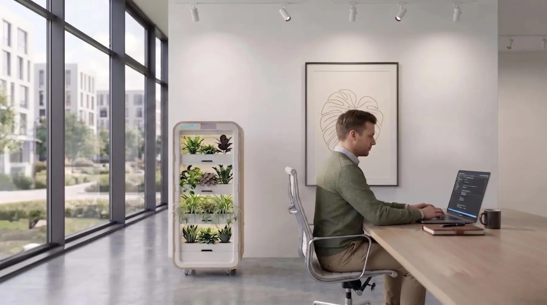 رجل يعمل على حاسوب محمول في مكتب حديث بجانب برج نباتي من Greenairy لتنقية الهواء وتحسين جودة الهواء الداخلي.