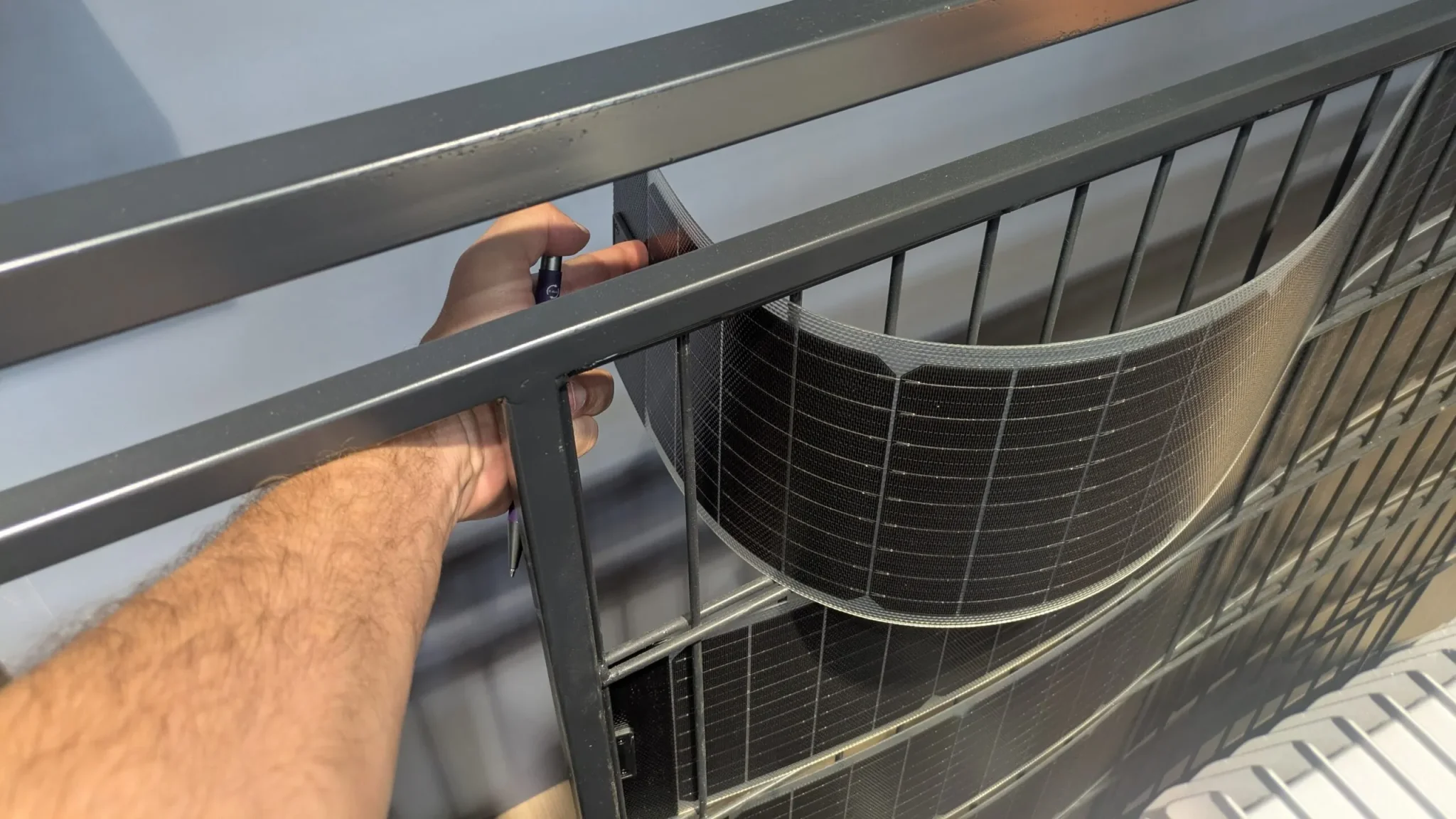 يد يثبت لوحة شمسية مرنة على شرفة، توضح نظام SolarVault 3 القابل للتركيب الذاتي لتخزين الطاقة الشمسية في الشقق.